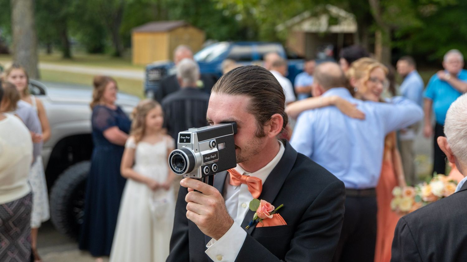 Wedding guests gathering outdoors in formal attire during a summer celebration.
