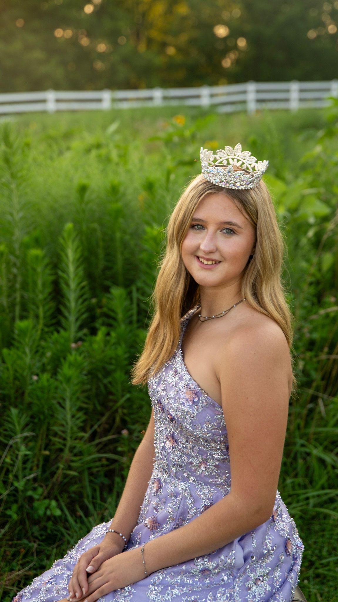 Outdoor portrait session featuring a sparkly purple gown and tiara among greenery.