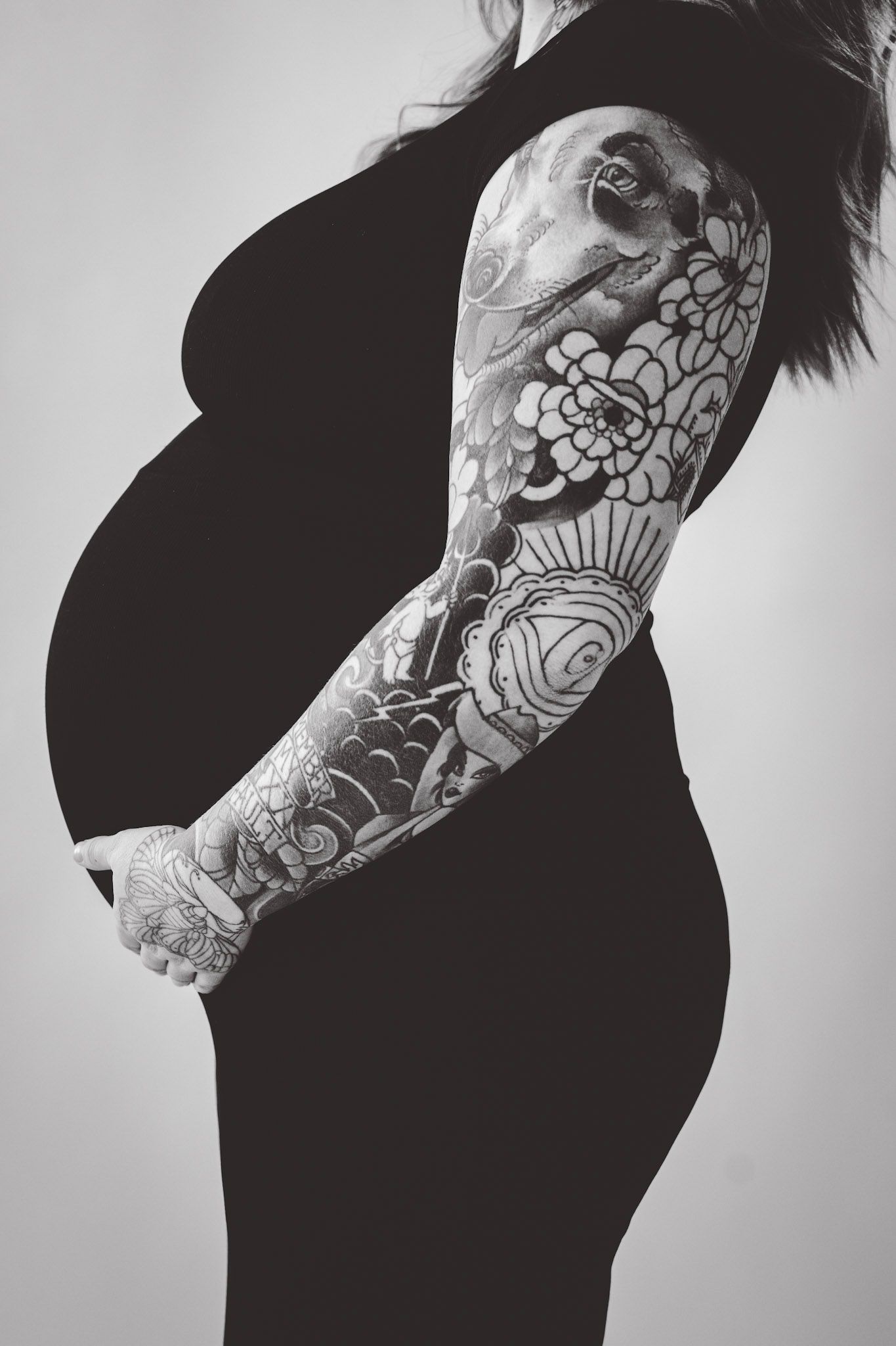 Black and white profile shots highlighting tattooed arm and pregnant belly.