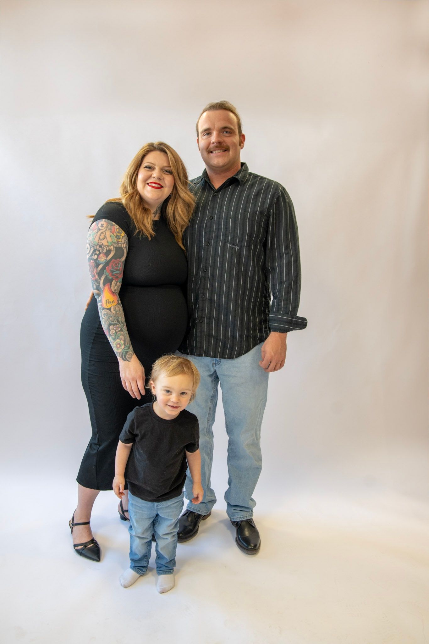Family portrait session with toddler in matching black outfits against white background.