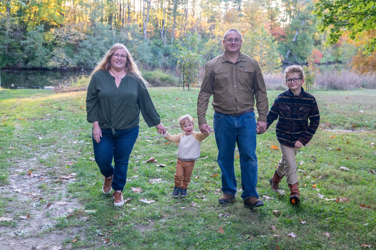 A family walking together through a scenic fall landscape with golden sunlight filtering through trees.