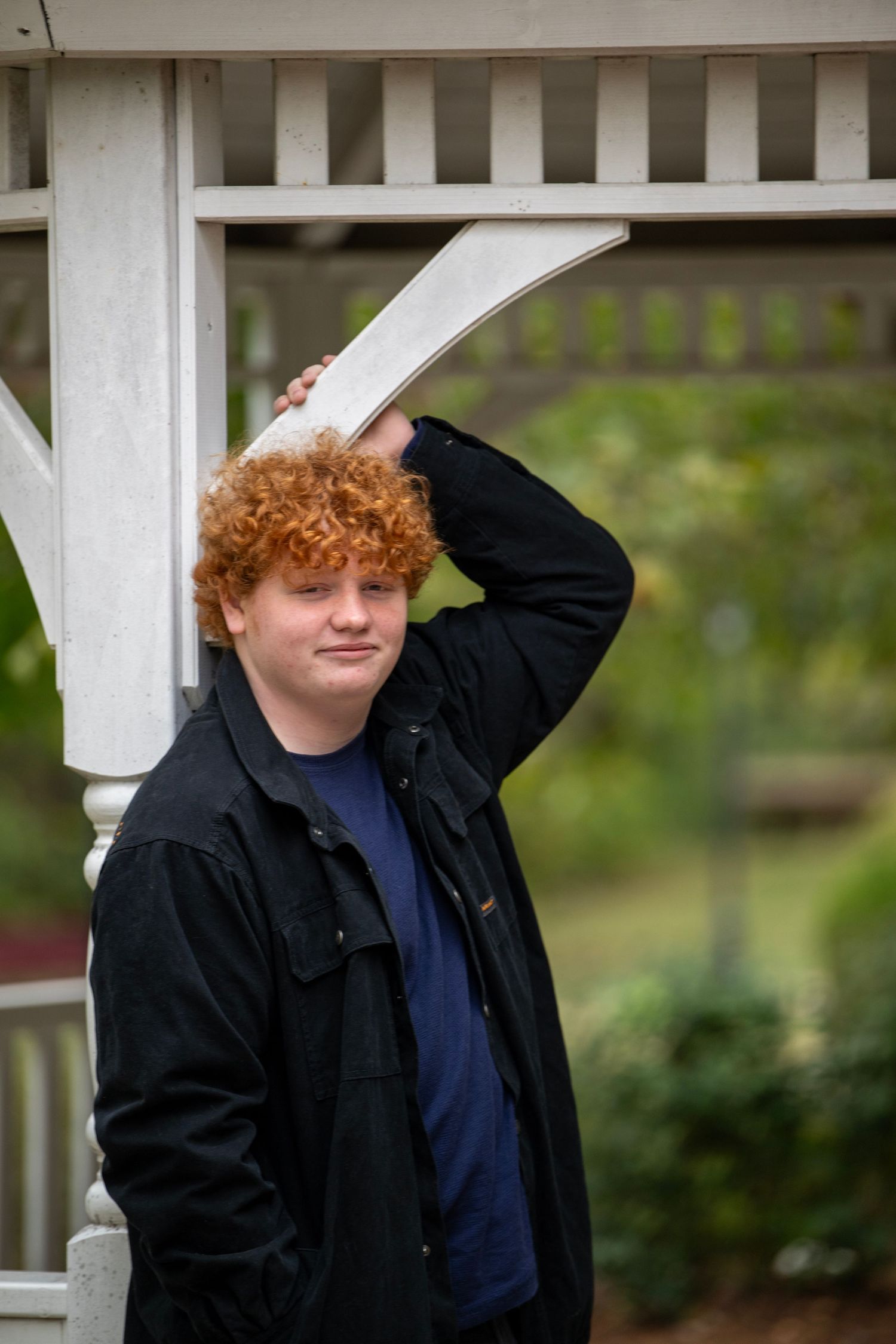 Portrait series against a white gazebo showing someone in a dark jacket and blue shirt.