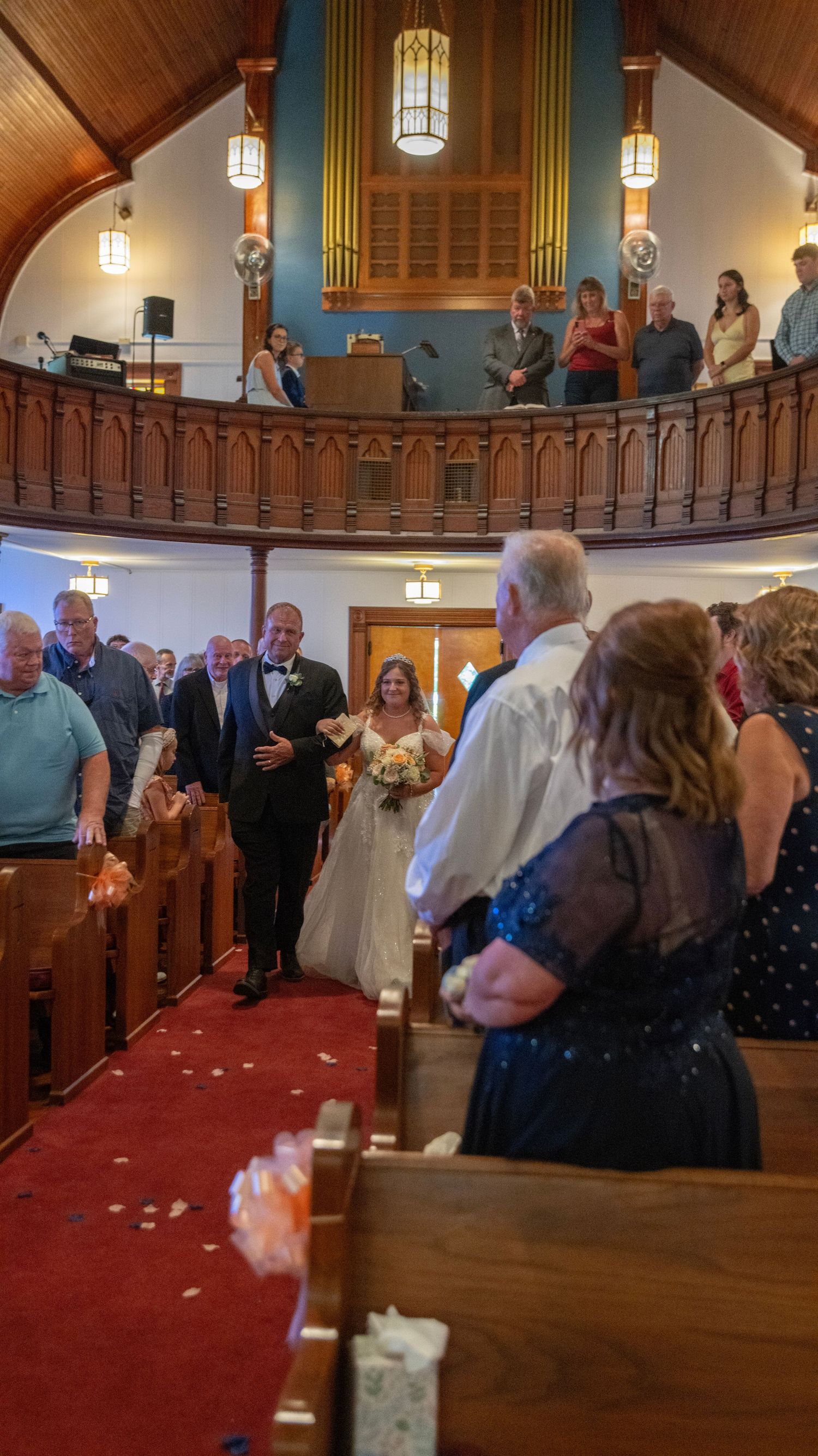 Church interior with wooden beams and red carpet during wedding ceremony.