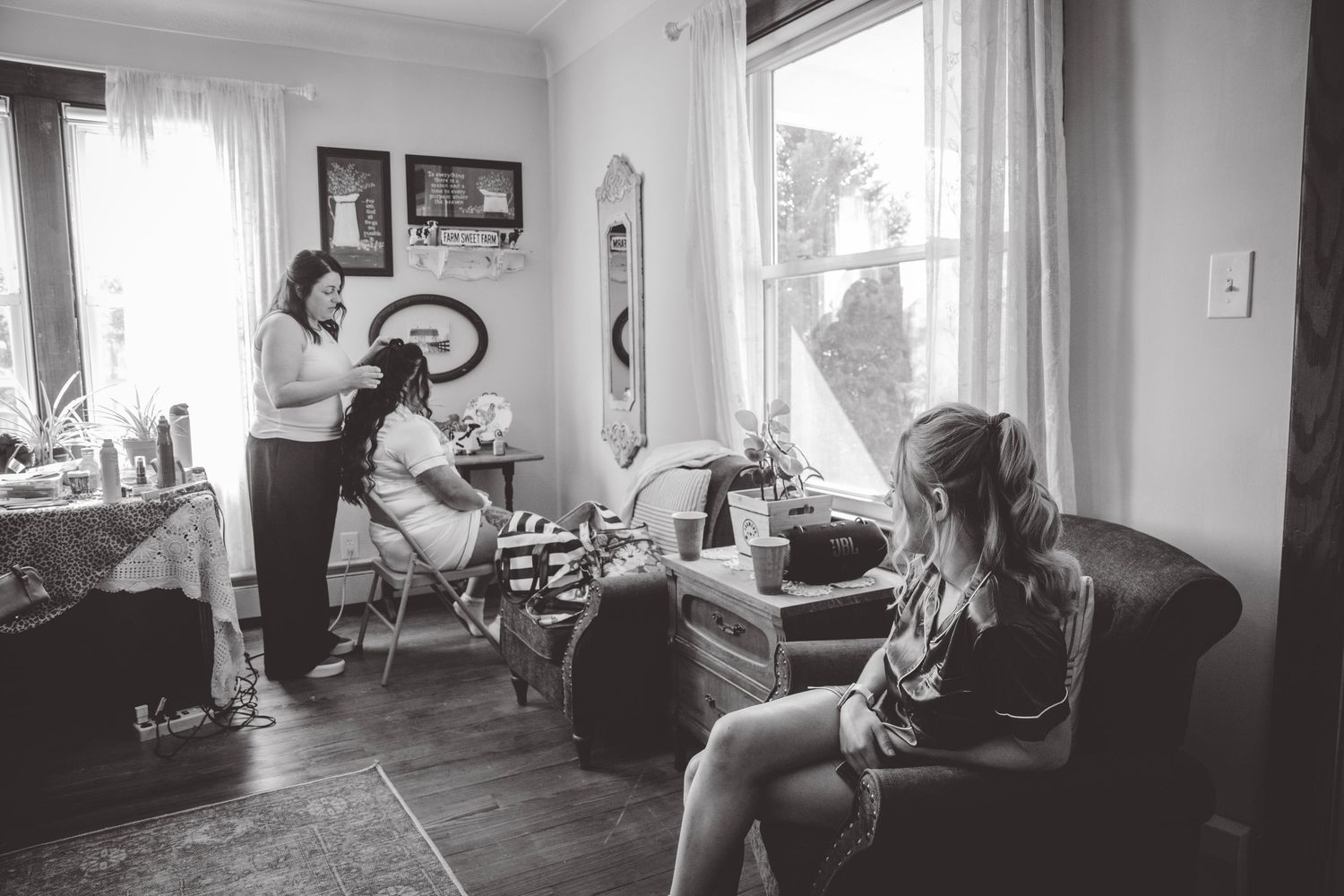 Black and white photo of wedding preparation scene in cozy living room with natural light.