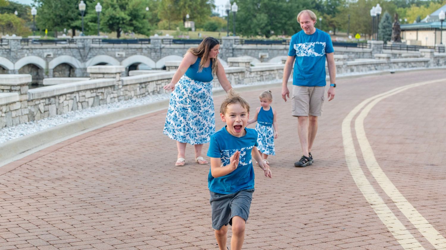 Family walking together along curved brick pathway in outdoor park setting.