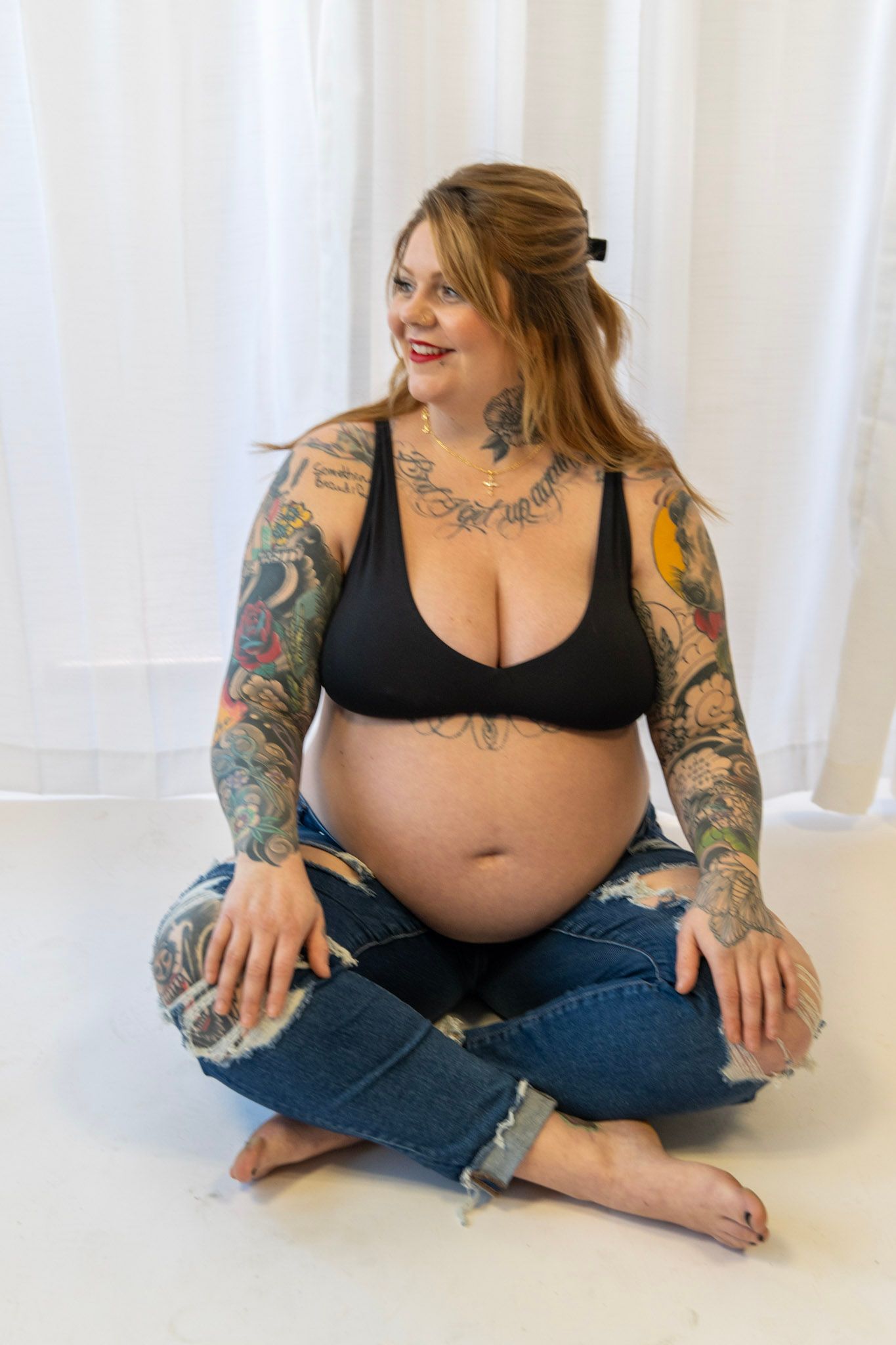 Candid maternity photos showing colorful arm tattoos and relaxed sitting poses.