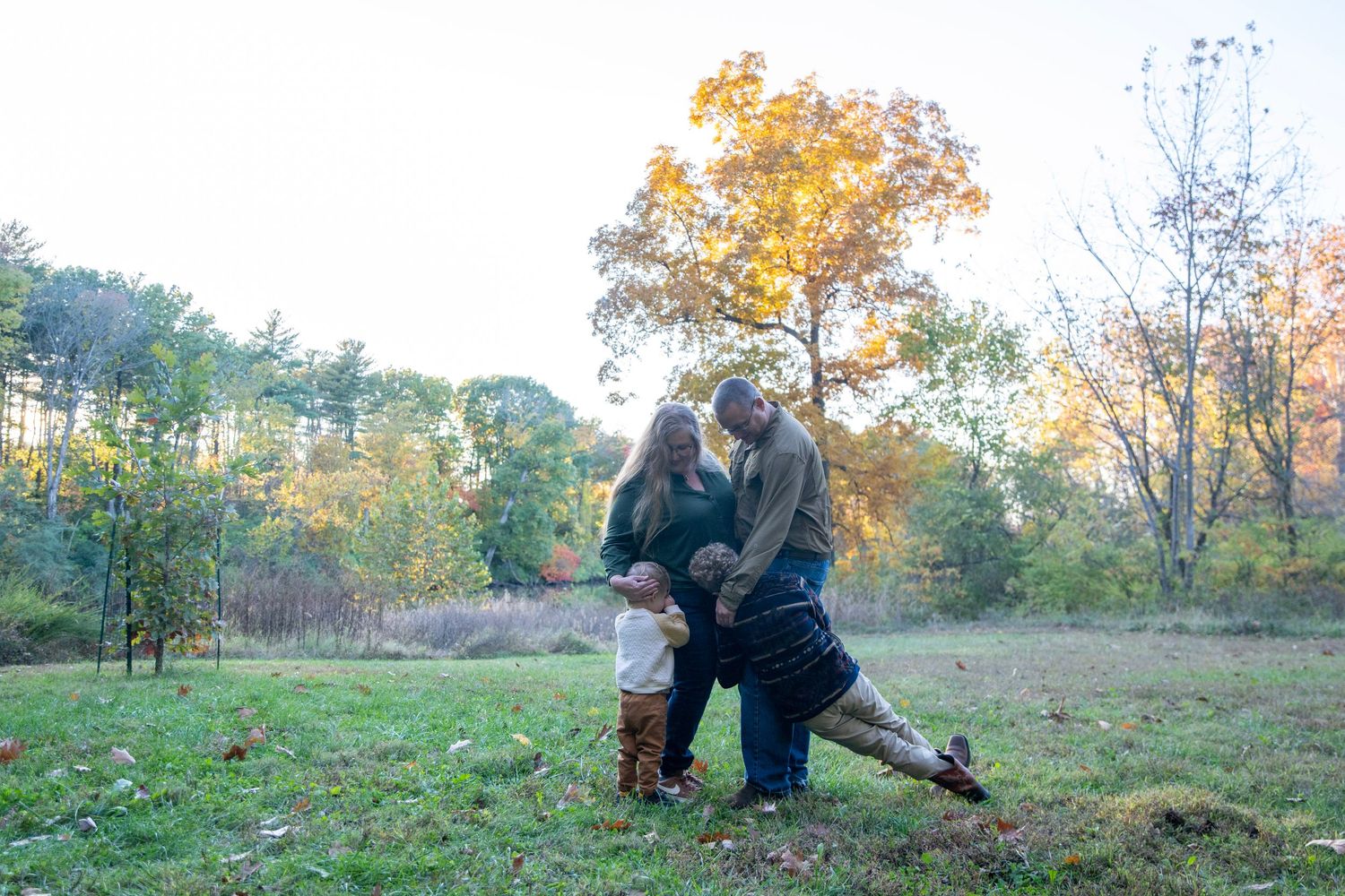 People walking together through a scenic autumn field surrounded by colorful fall foliage.