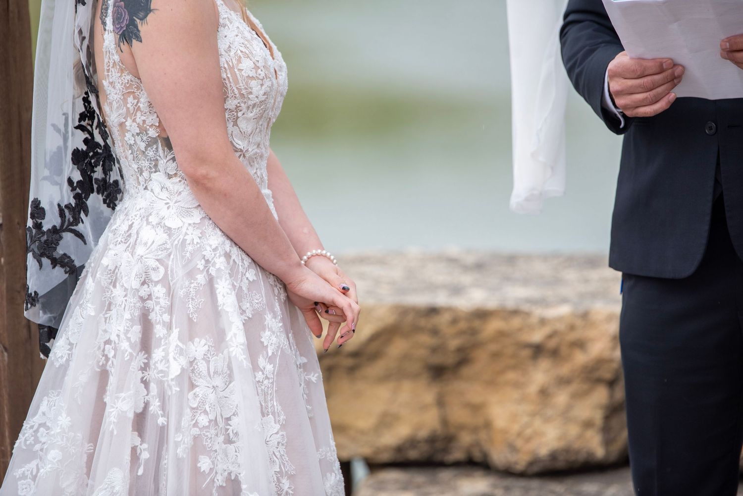 Couple exchanging vows during outdoor wedding ceremony with purple and white decor elements.