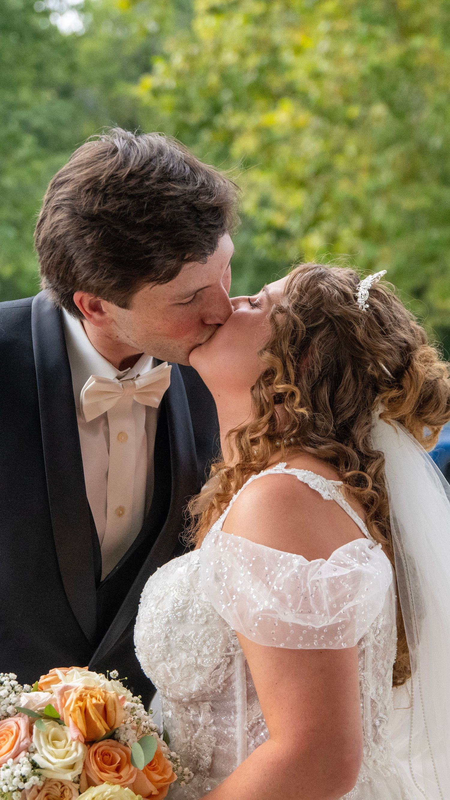 Romantic outdoor wedding moment with peach and orange floral bouquet details.