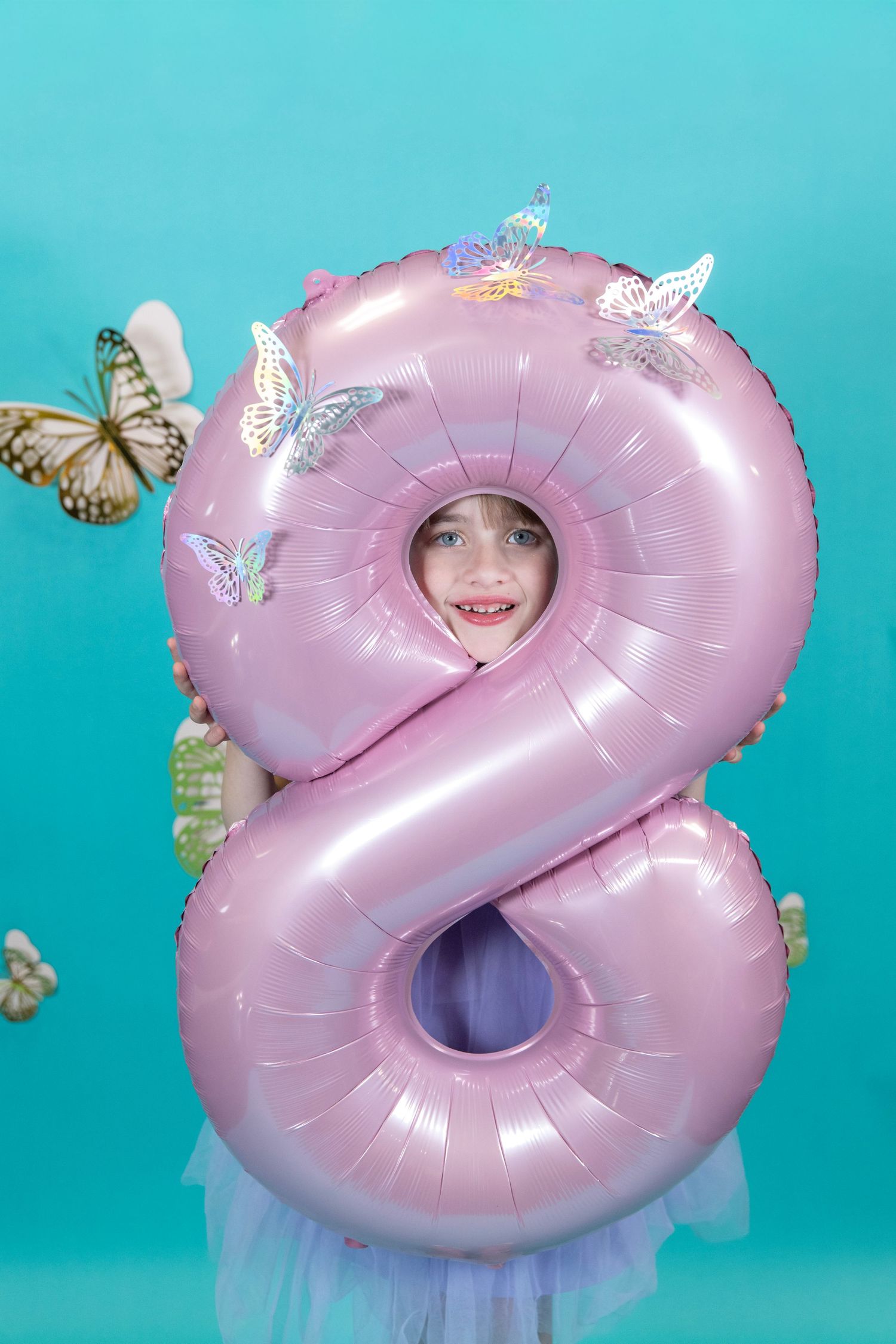 Creative portrait through pink number 2 balloon with butterflies floating around.
