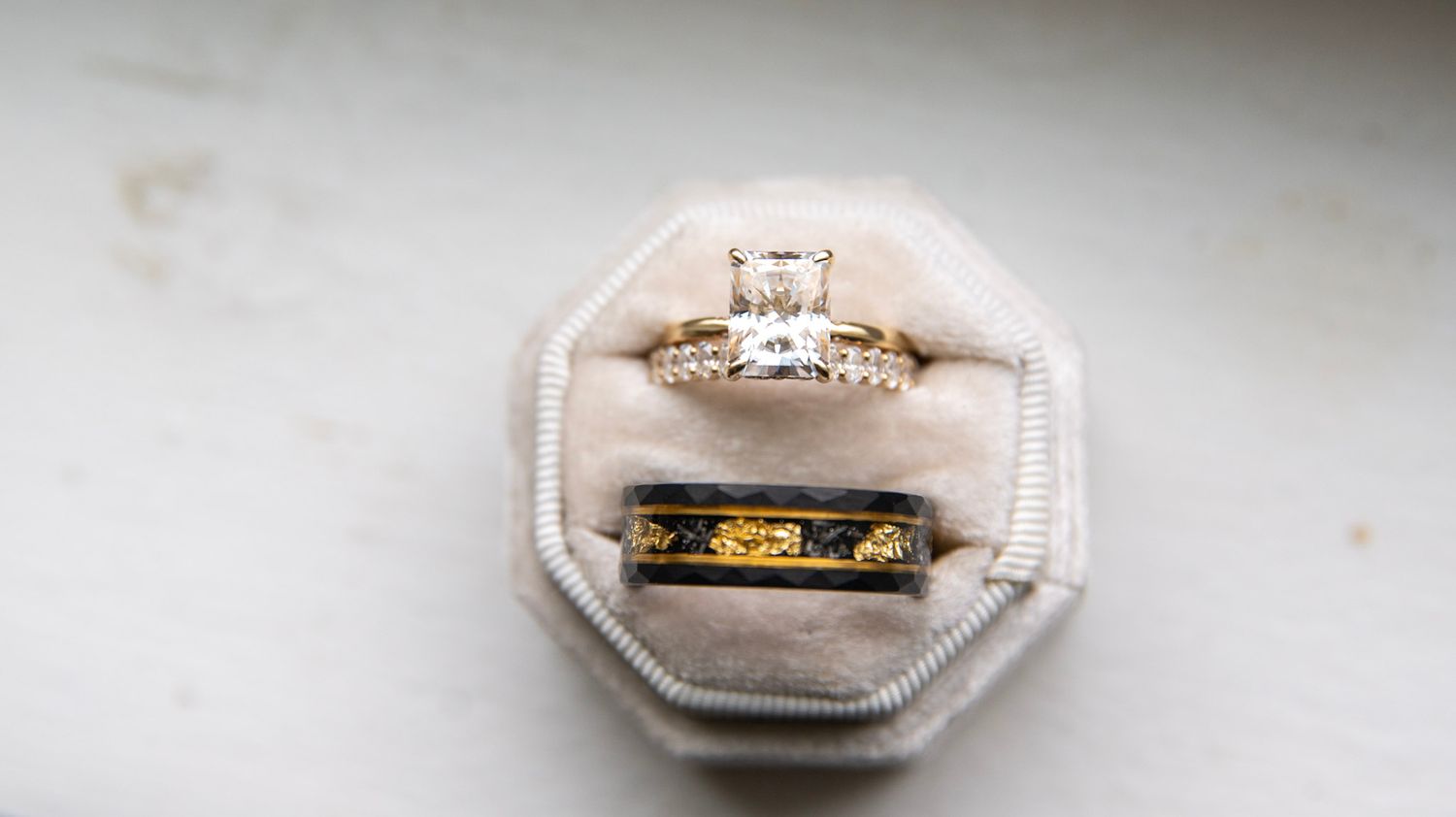 Elegant engagement and wedding rings displayed on white surface.