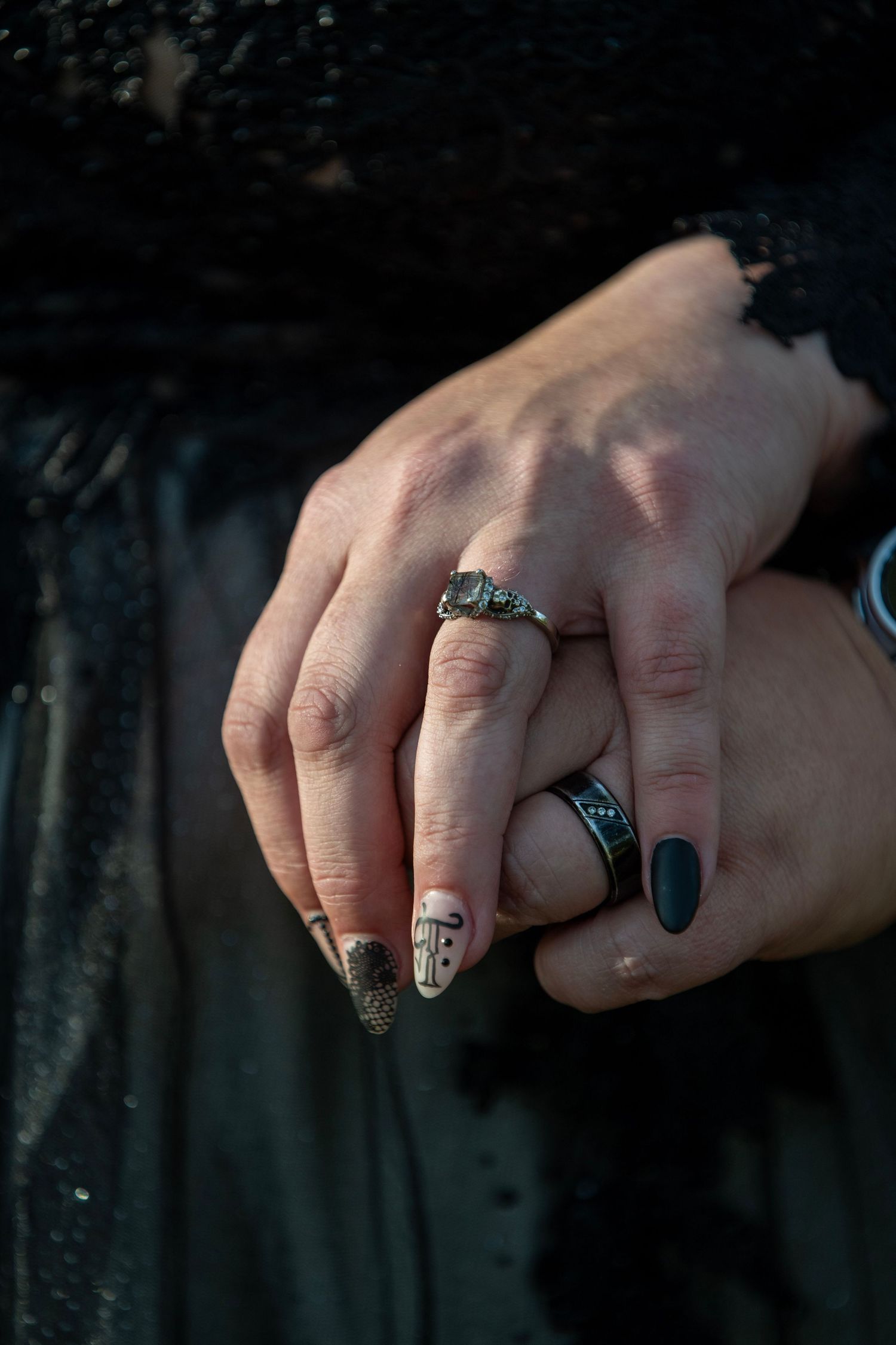 Close-up shot of hands wearing decorative rings against a dark background.