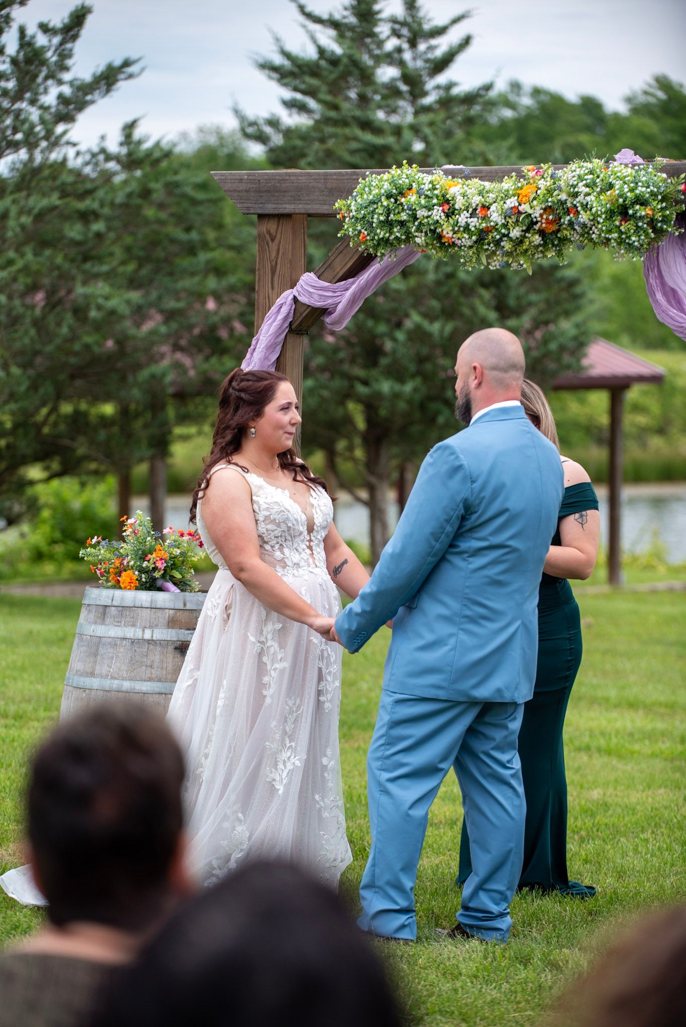 Wedding ceremony taking place on a grassy lawn with guests watching the couple exchange vows.