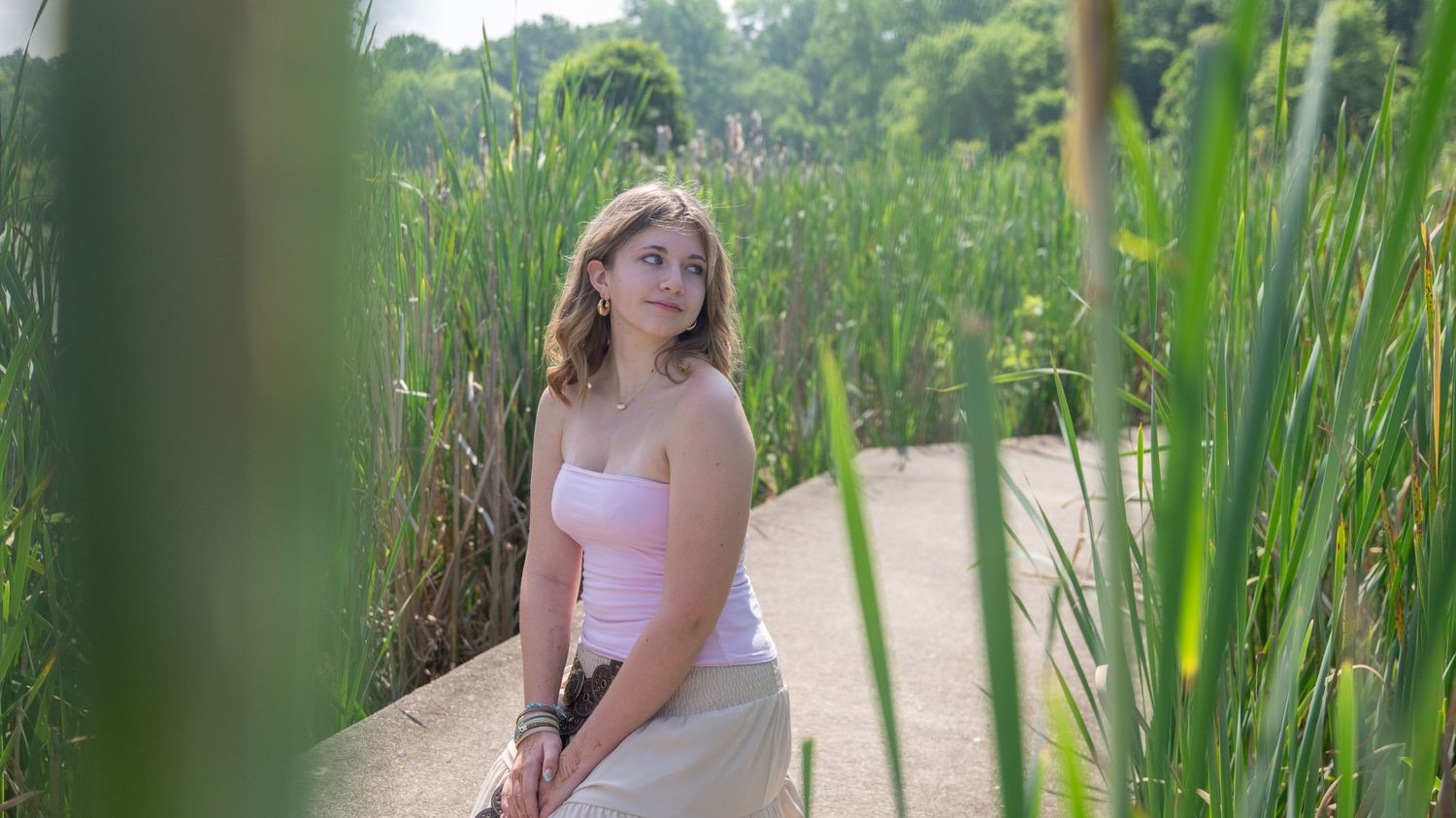 A woman wearing a floral crown poses in a natural outdoor setting with lush greenery.