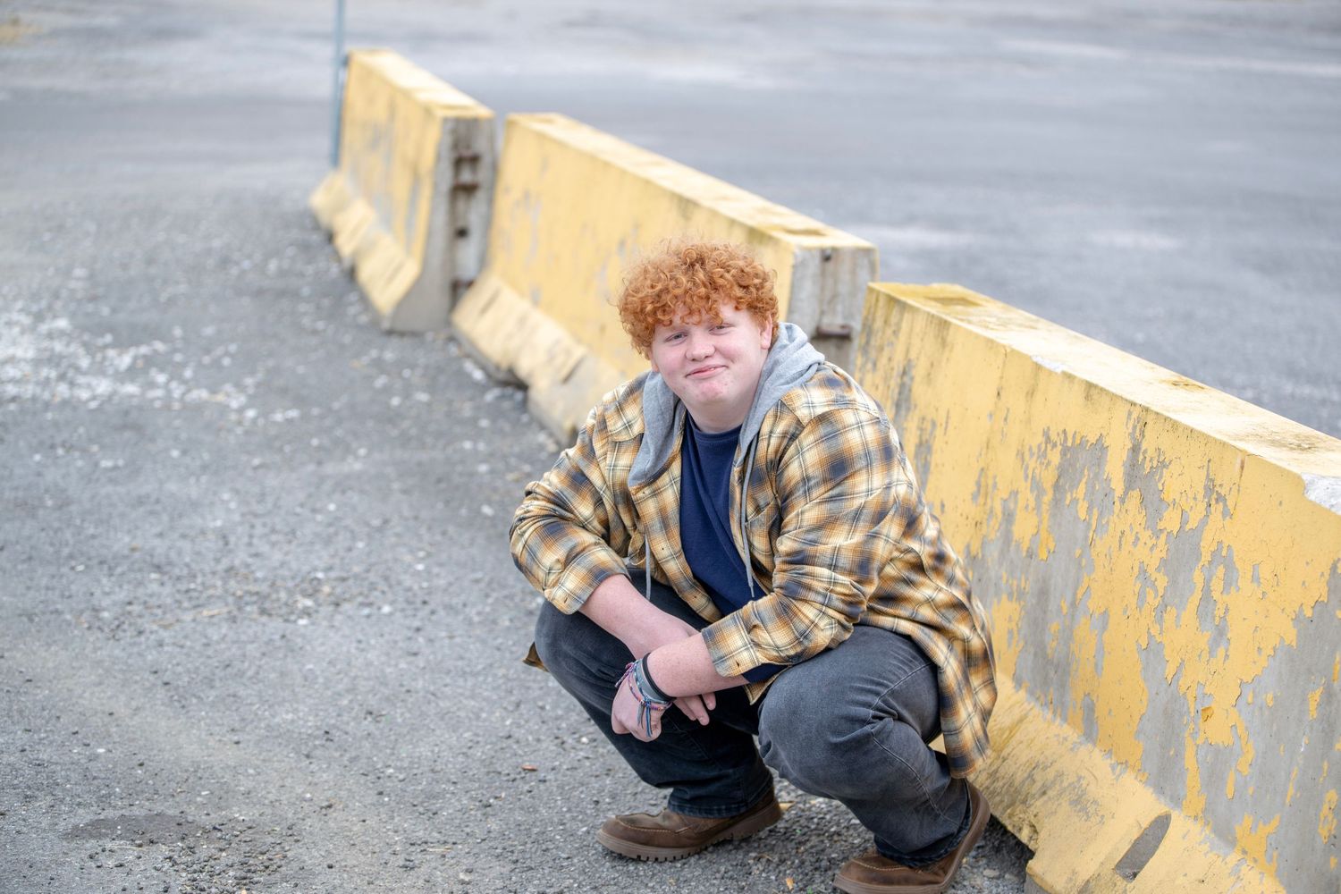 Crouching poses on gravel surface near yellow barrier during photo session.