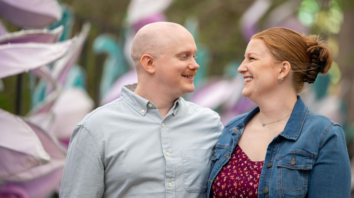 Couple laughing together outdoors with spring flowers in the background.