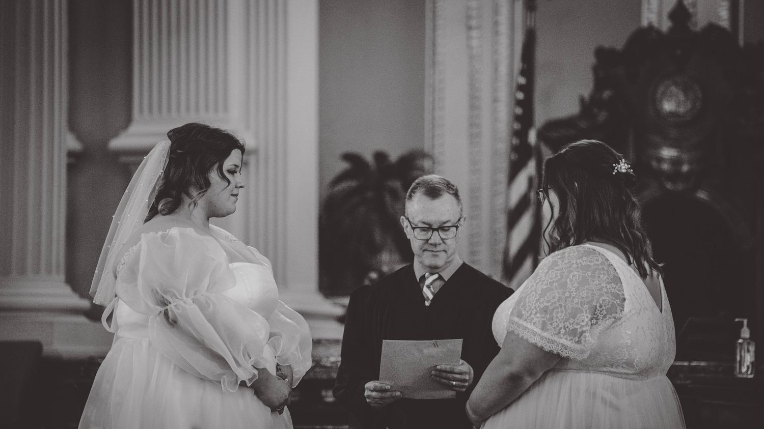 A black and white panoramic view of a wedding ceremony in an elegant church setting.