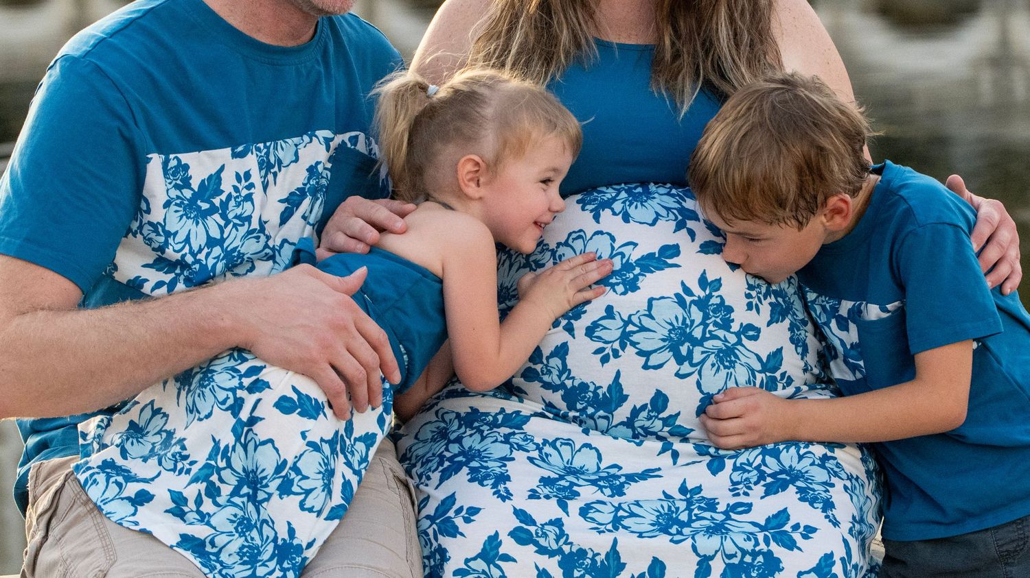 Close-up detail of family members embracing in coordinating blue and white floral patterns.