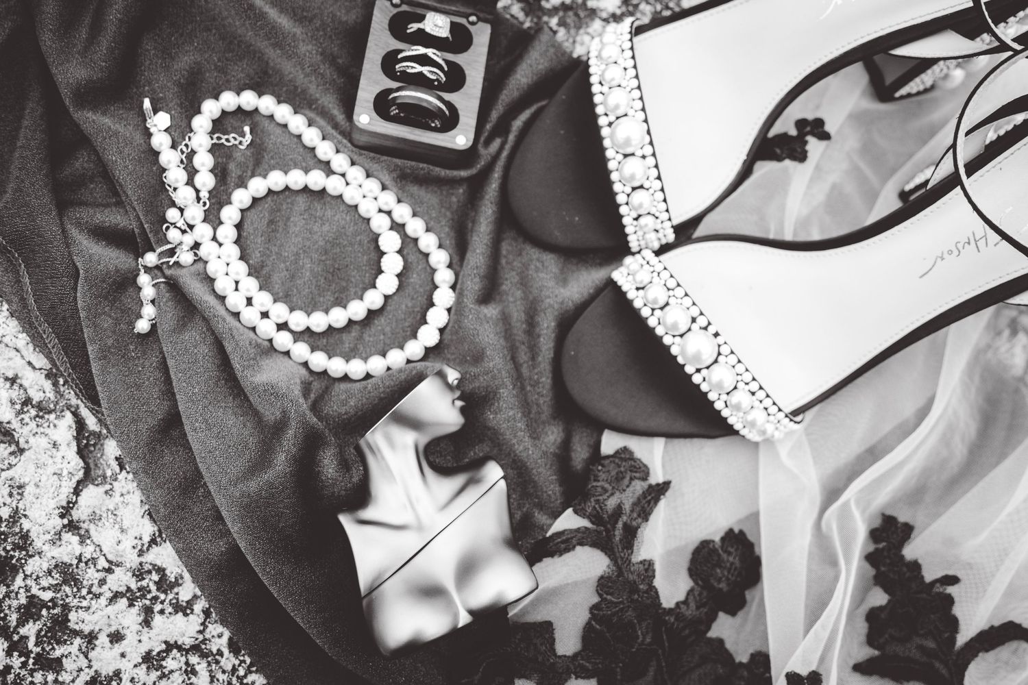 Wedding accessories including pearl necklaces and decorative items arranged in black and white.