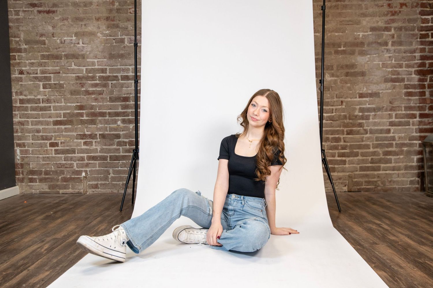 Portrait session against brick wall and white backdrop showing casual poses on wooden floor.