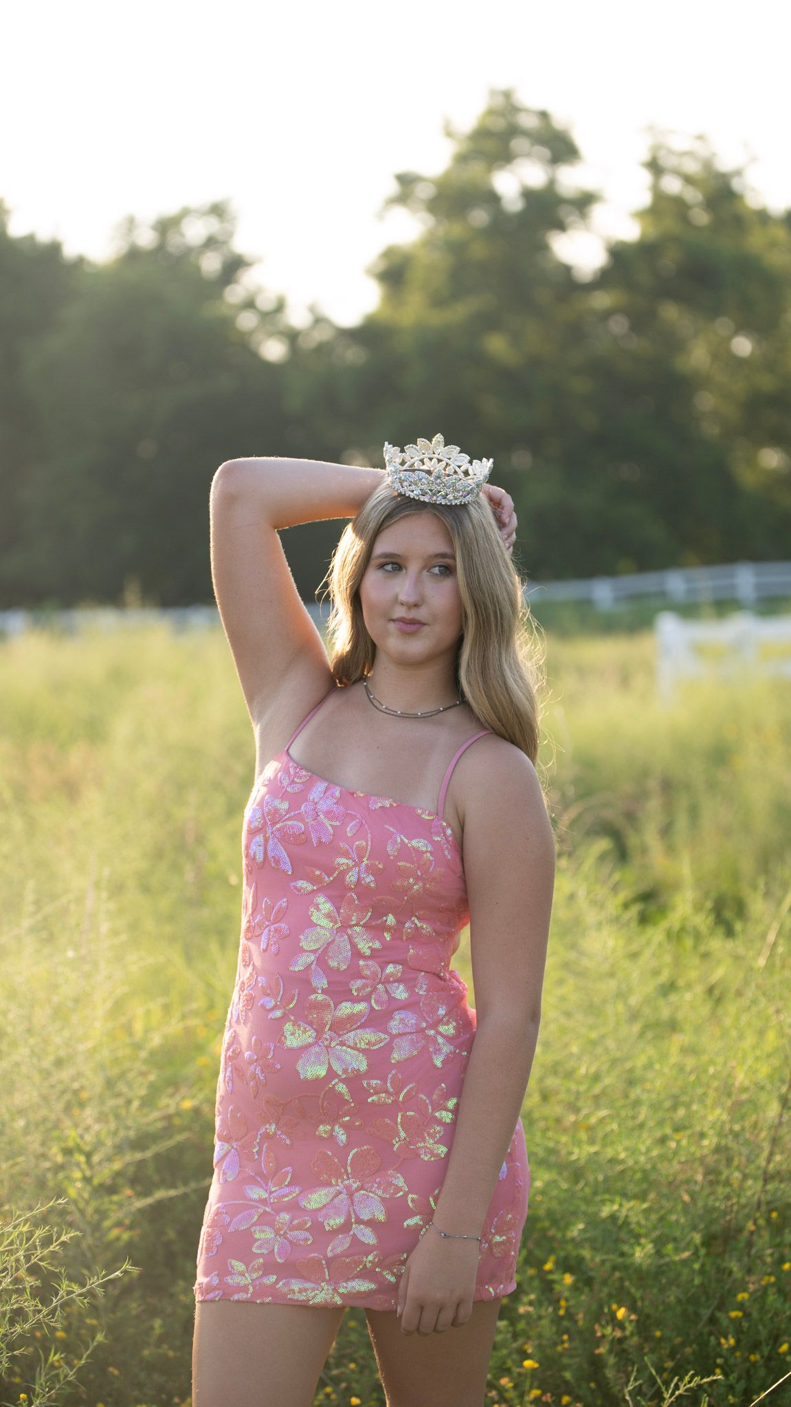 Summer portrait in a pink floral top against a sunlit meadow background.