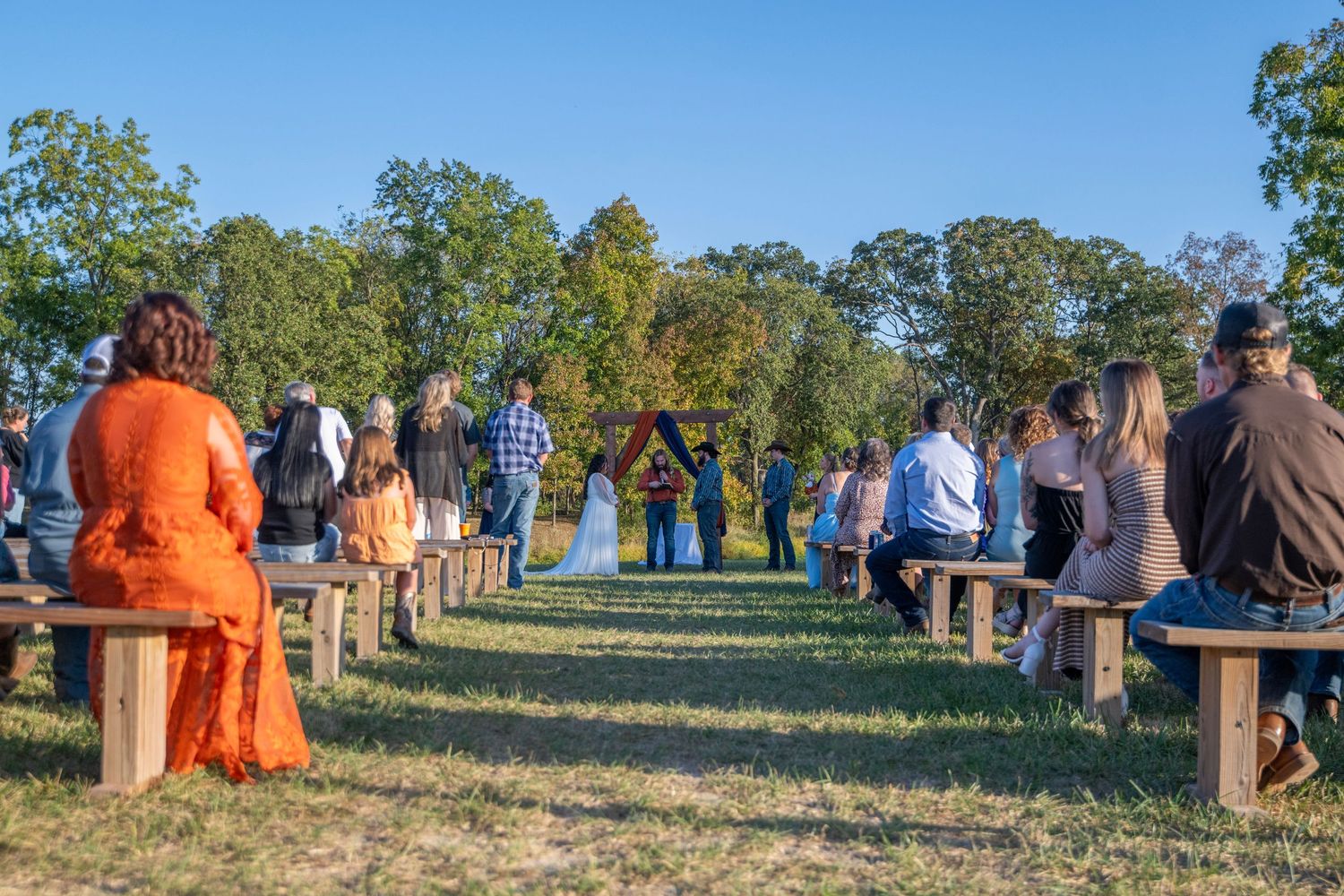 Panoramic view of wedding guests gathered on a hilltop during sunset.