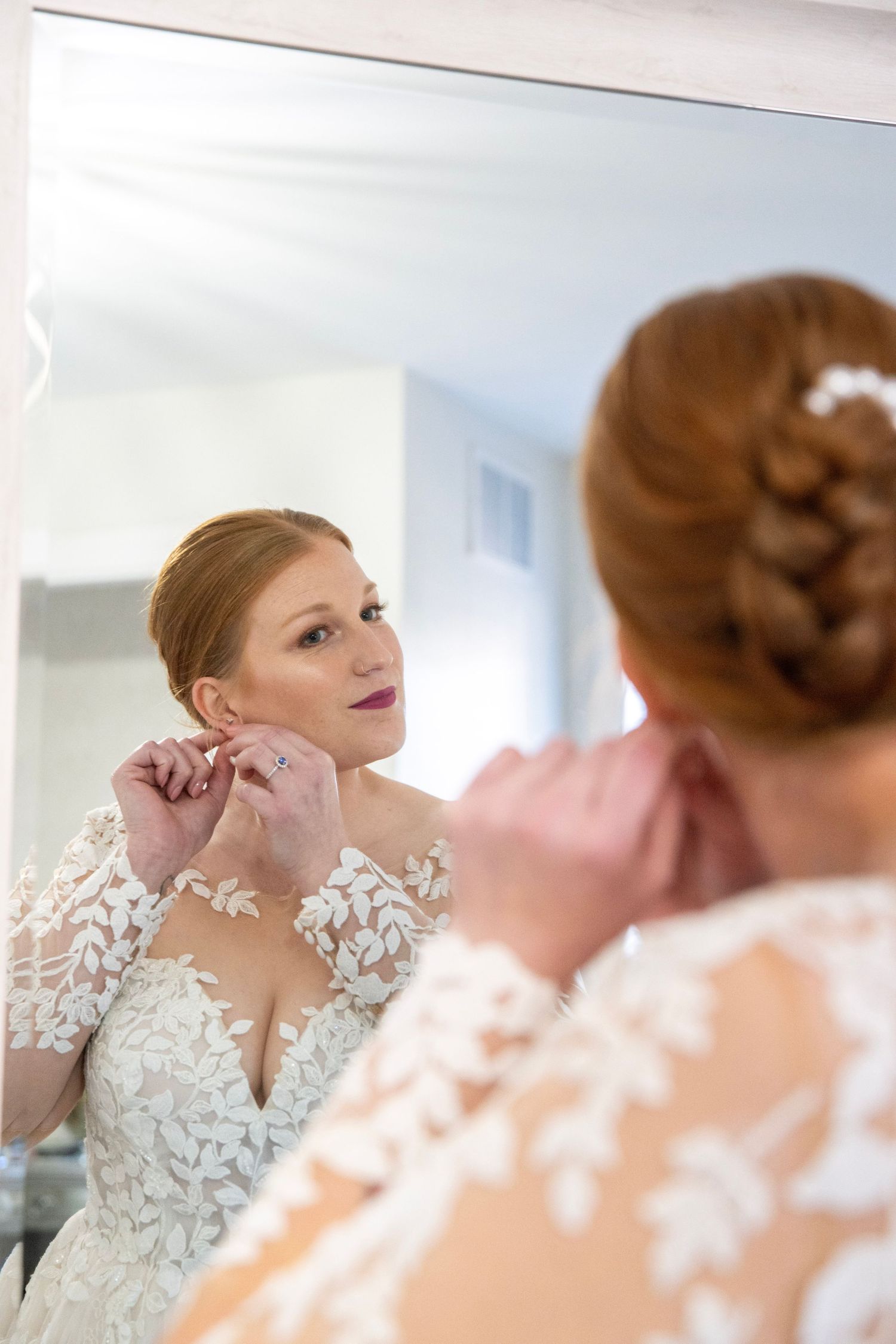 Wedding preparation scene showing final touches and adjustments in mirror reflection.