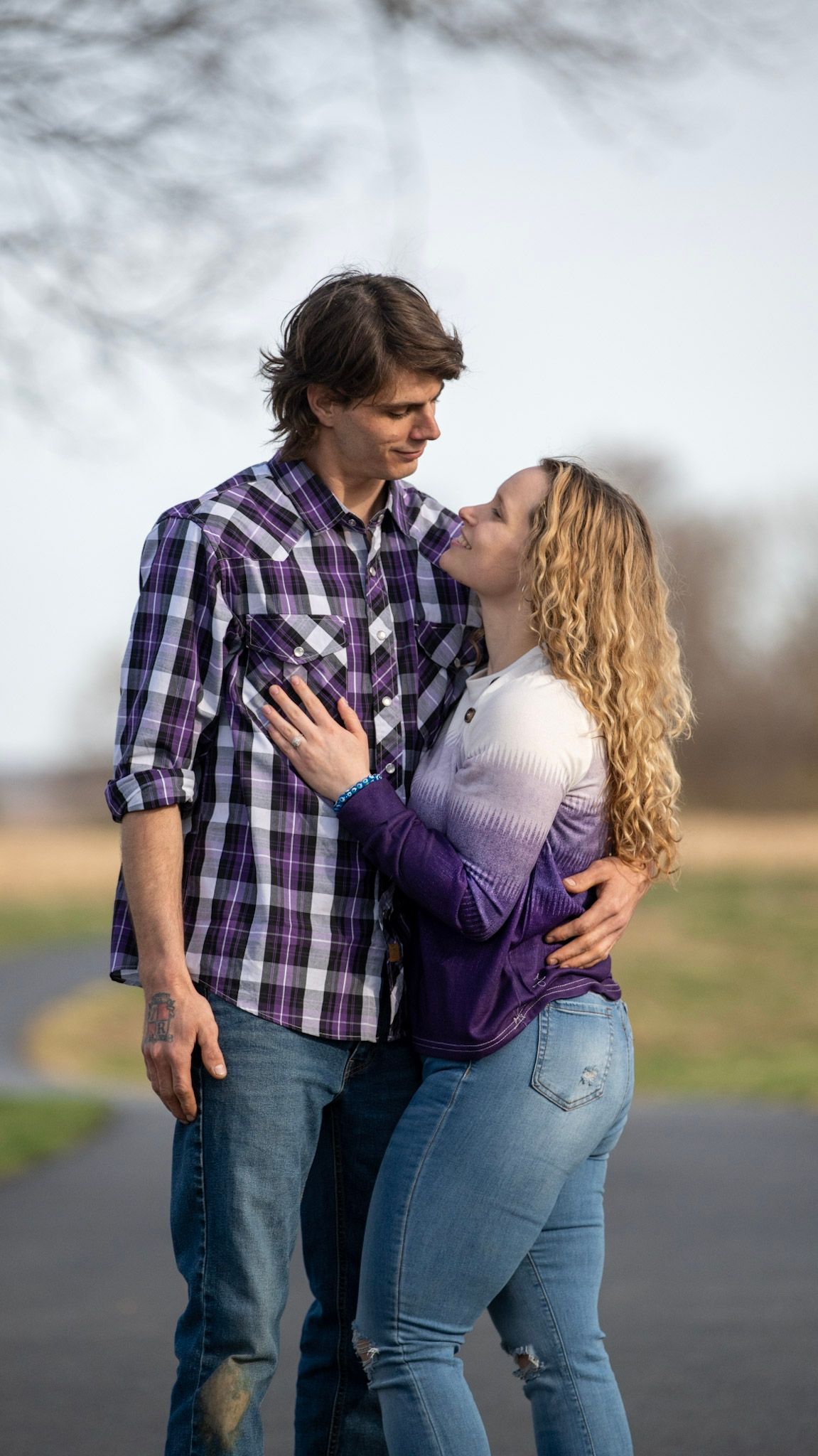 Romantic couple in purple and plaid sharing intimate moments on a country road.