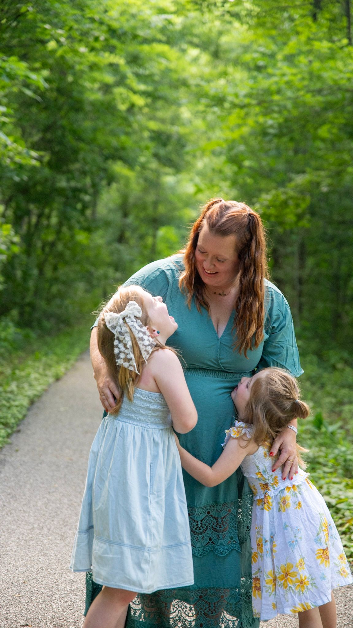A tender family moment captured on a tree-lined path in summer.