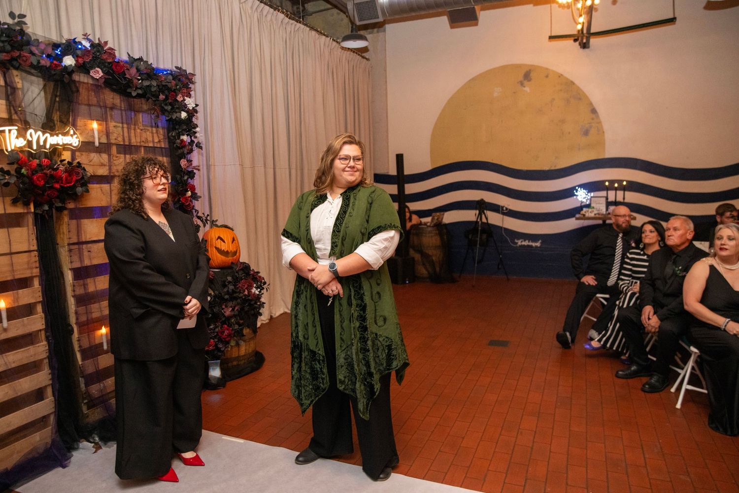 Reception area with decorative lighting and floral arrangements against a wooden wall.