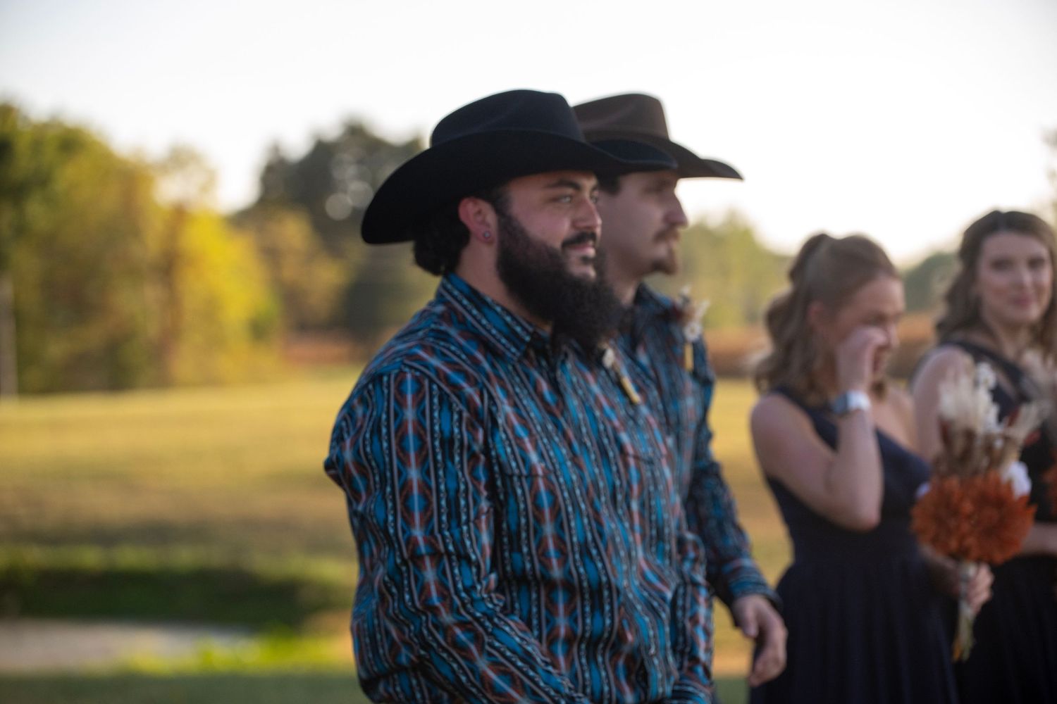 Group wearing cowboy hats and western shirts pose together at an outdoor event.