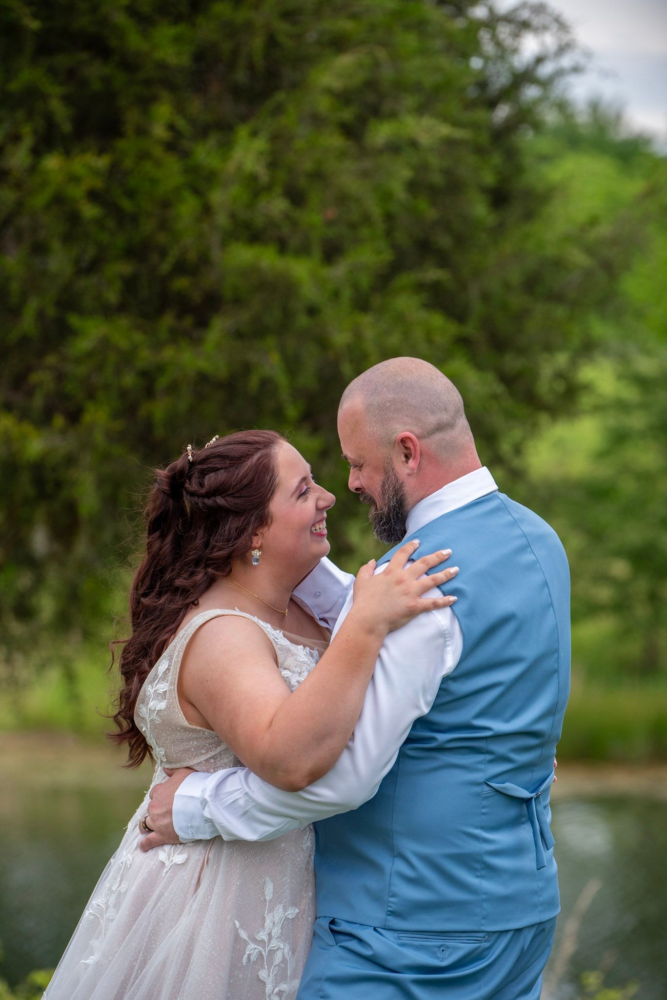 Emotional wedding ceremony moments captured by a lake with natural greenery in background.
