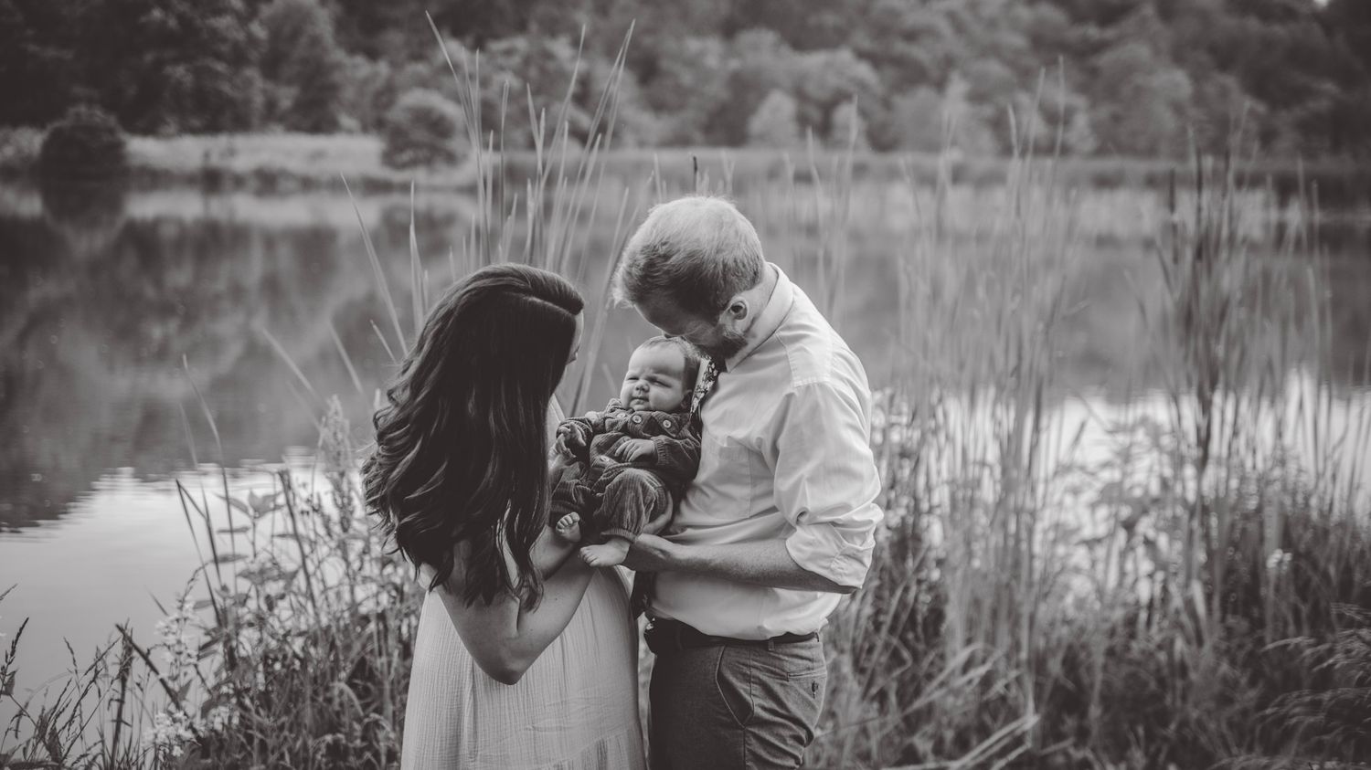 A black and white panoramic series of intimate family moments by a lake.