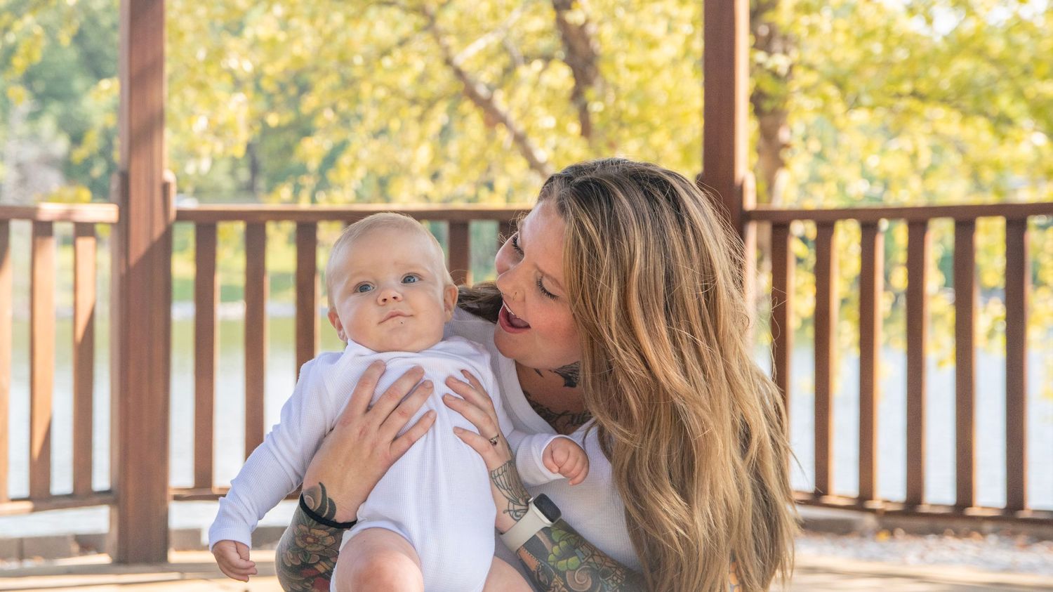 Family enjoying autumn day on wooden deck overlooking scenic lake view.