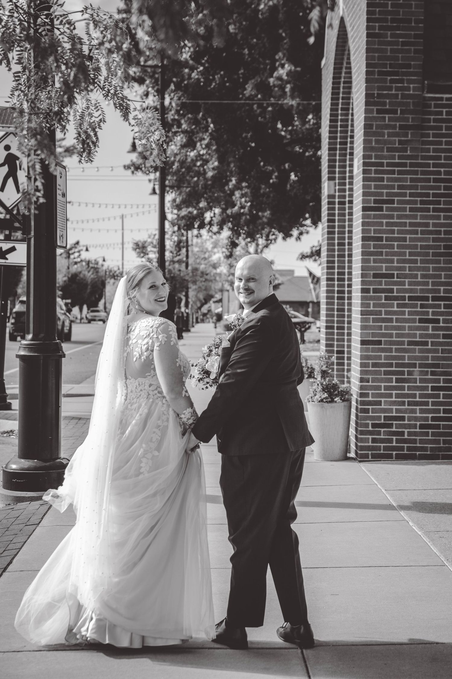 Black and white wedding photos showing a couple walking together outside a brick building.