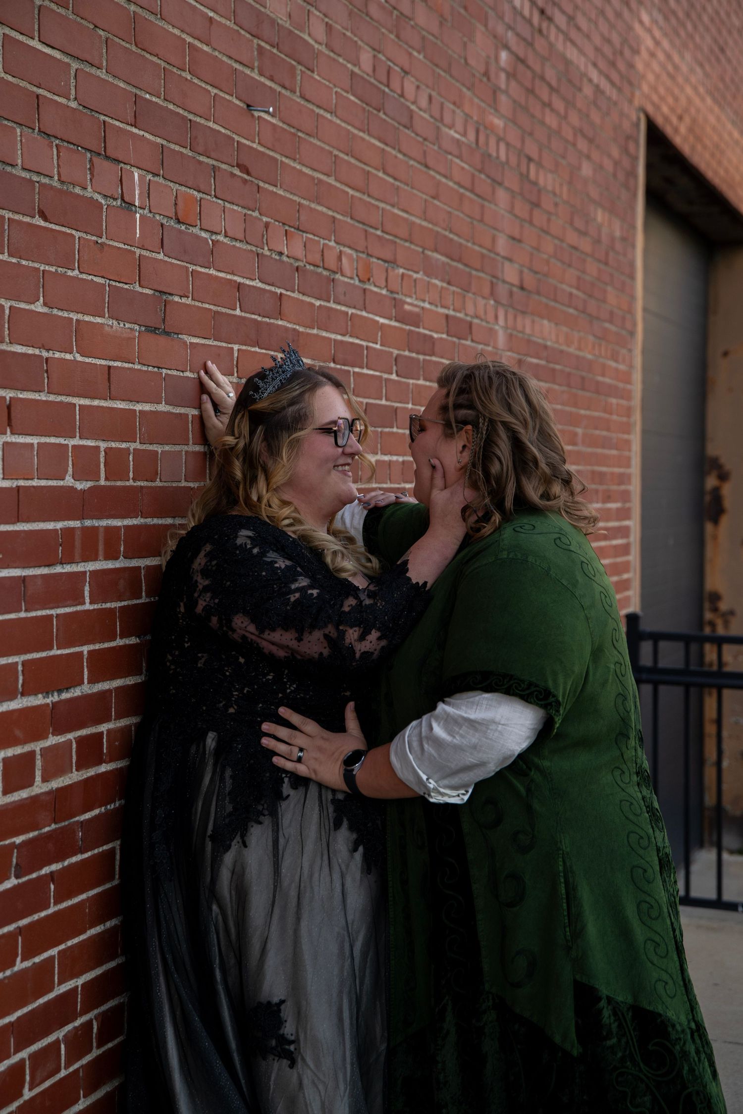 Couple sharing a moment against a red brick wall.