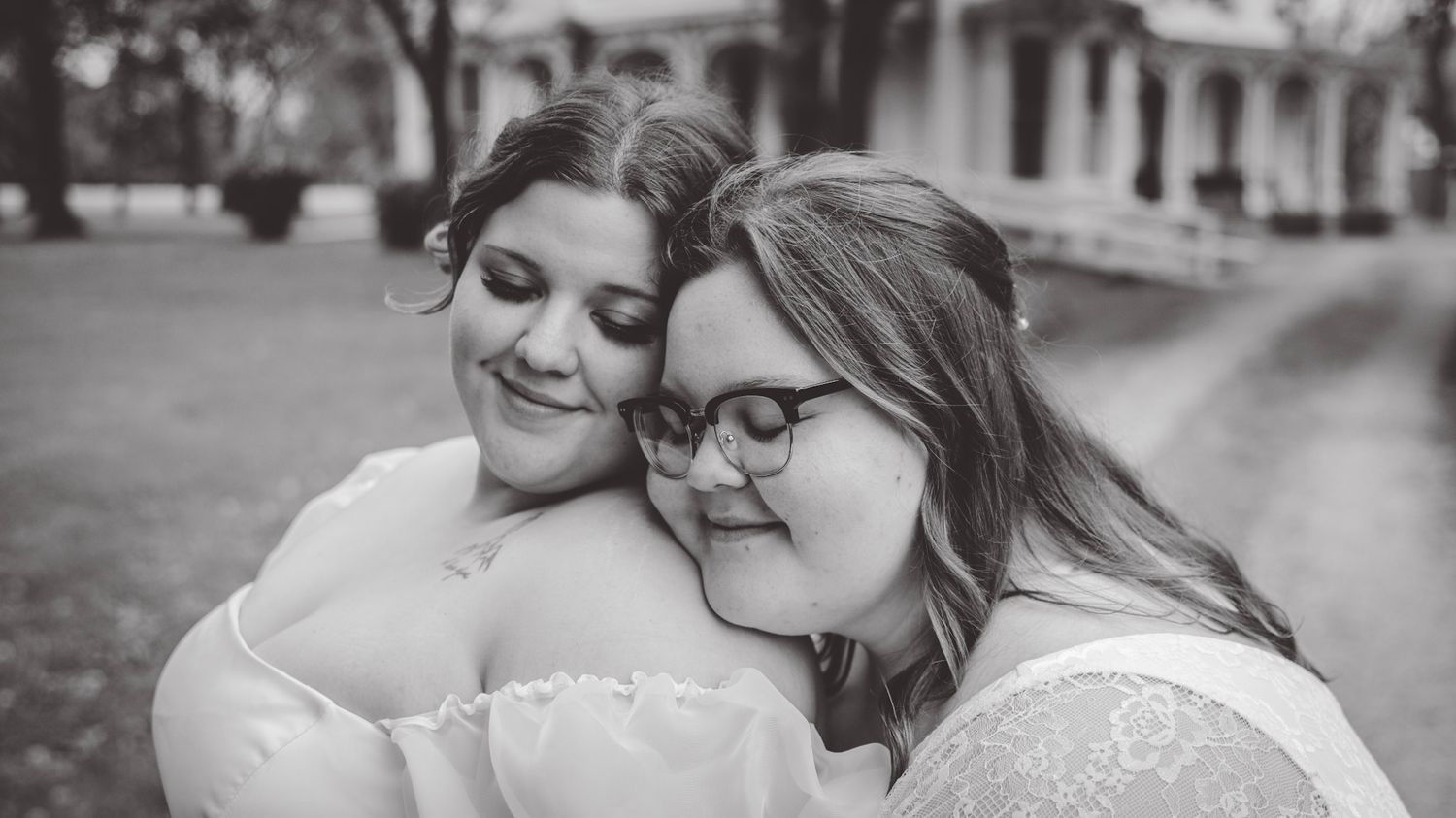 Black and white portrait of a couple in wedding attire sharing a close moment.