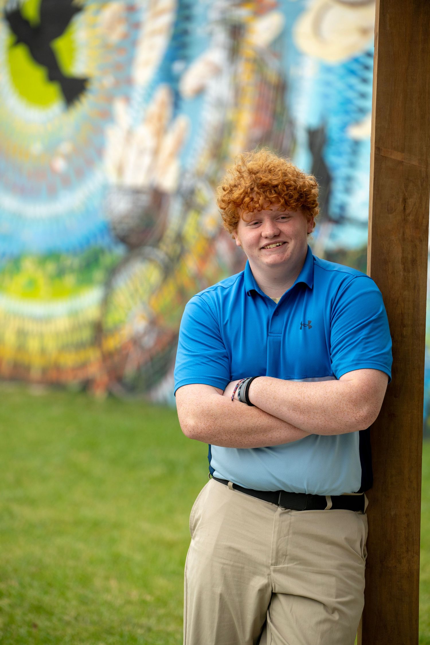 Casual portraits in blue polo against colorful mural background with natural lighting.