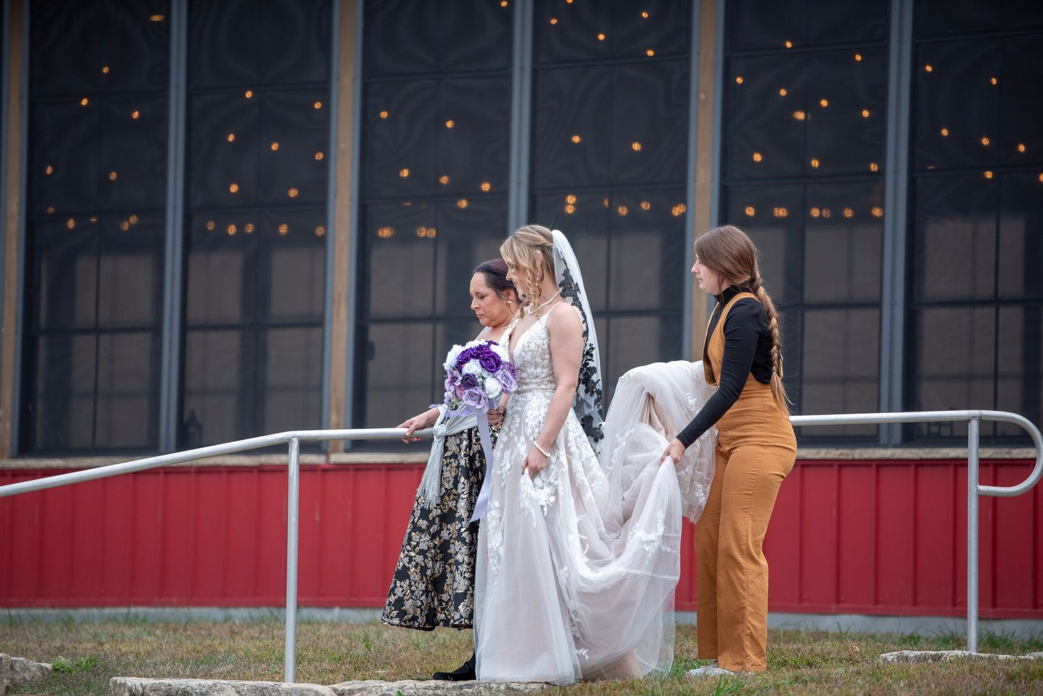 Wedding venue exterior with string lights and guests gathering outside.