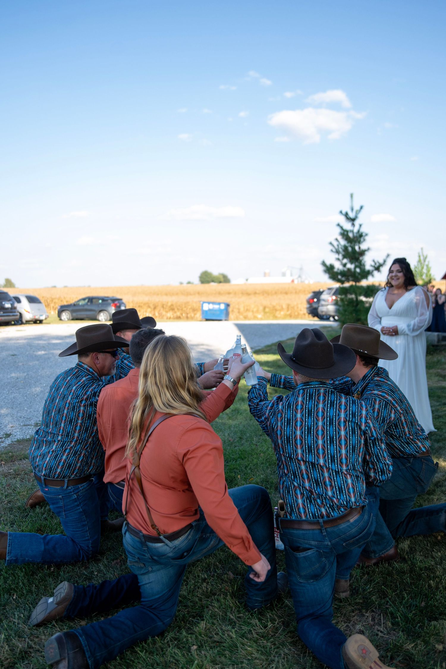 People in western clothing relax on the grass during an outdoor gathering.