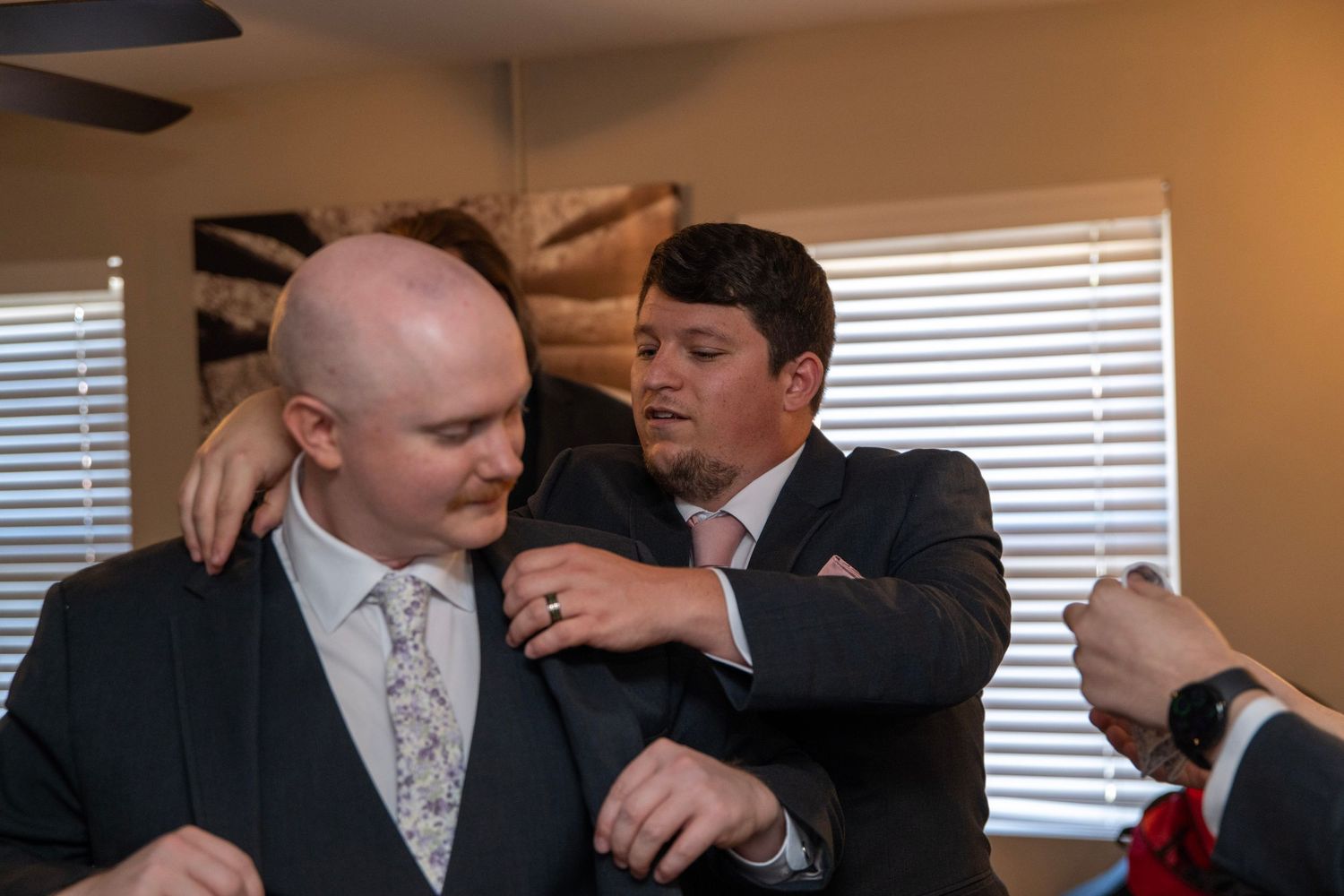 Group adjusting formal wear and ties while getting ready indoors.