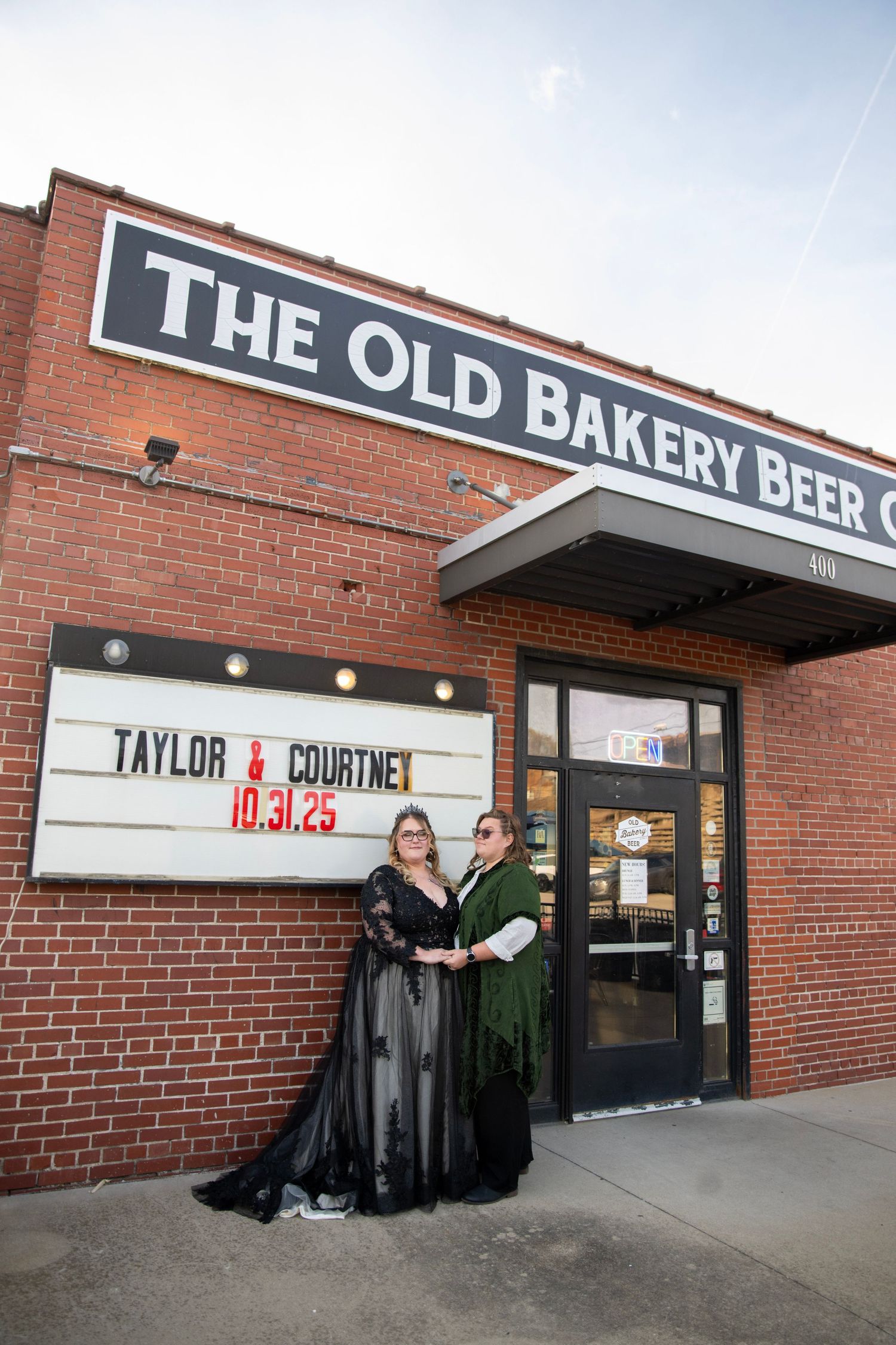 Couple posing outside The Old Bakery Beer Company brick building.
