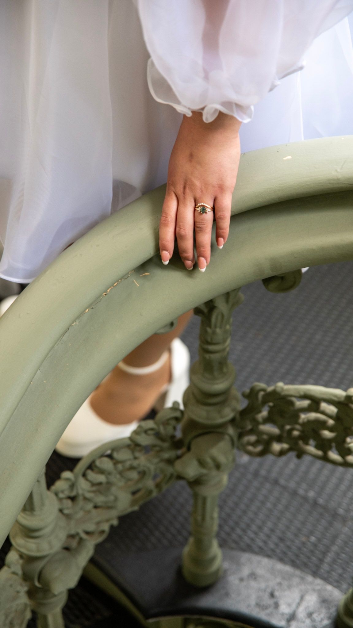 Close-up series of a wedding ring on hand against mint green vintage railing.