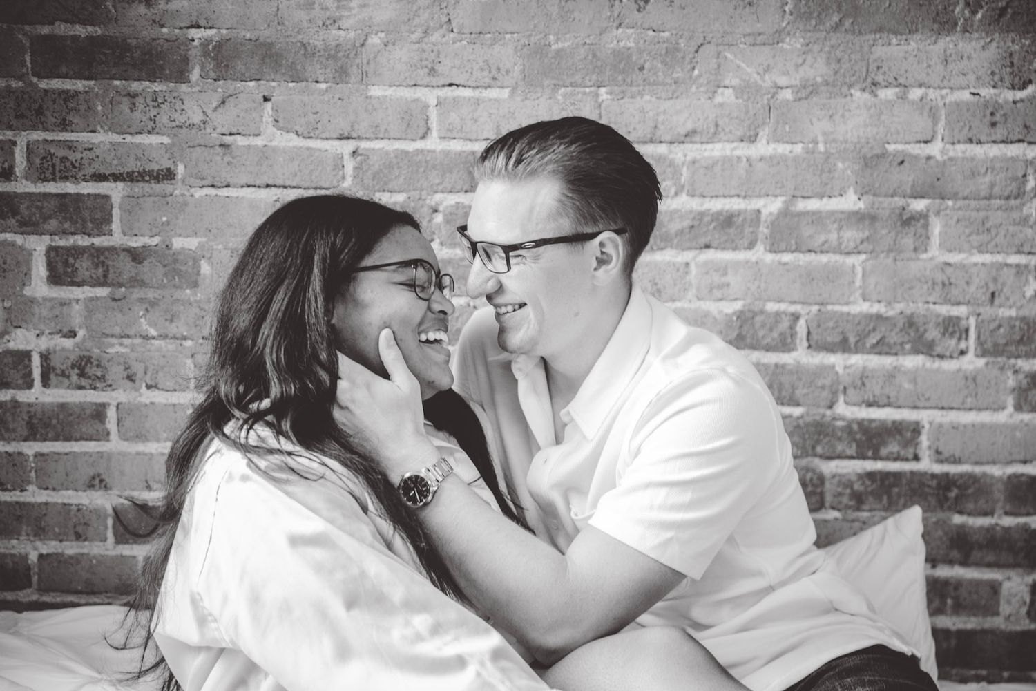 Artistic black and white series showing couple's tender interaction on white bedding.