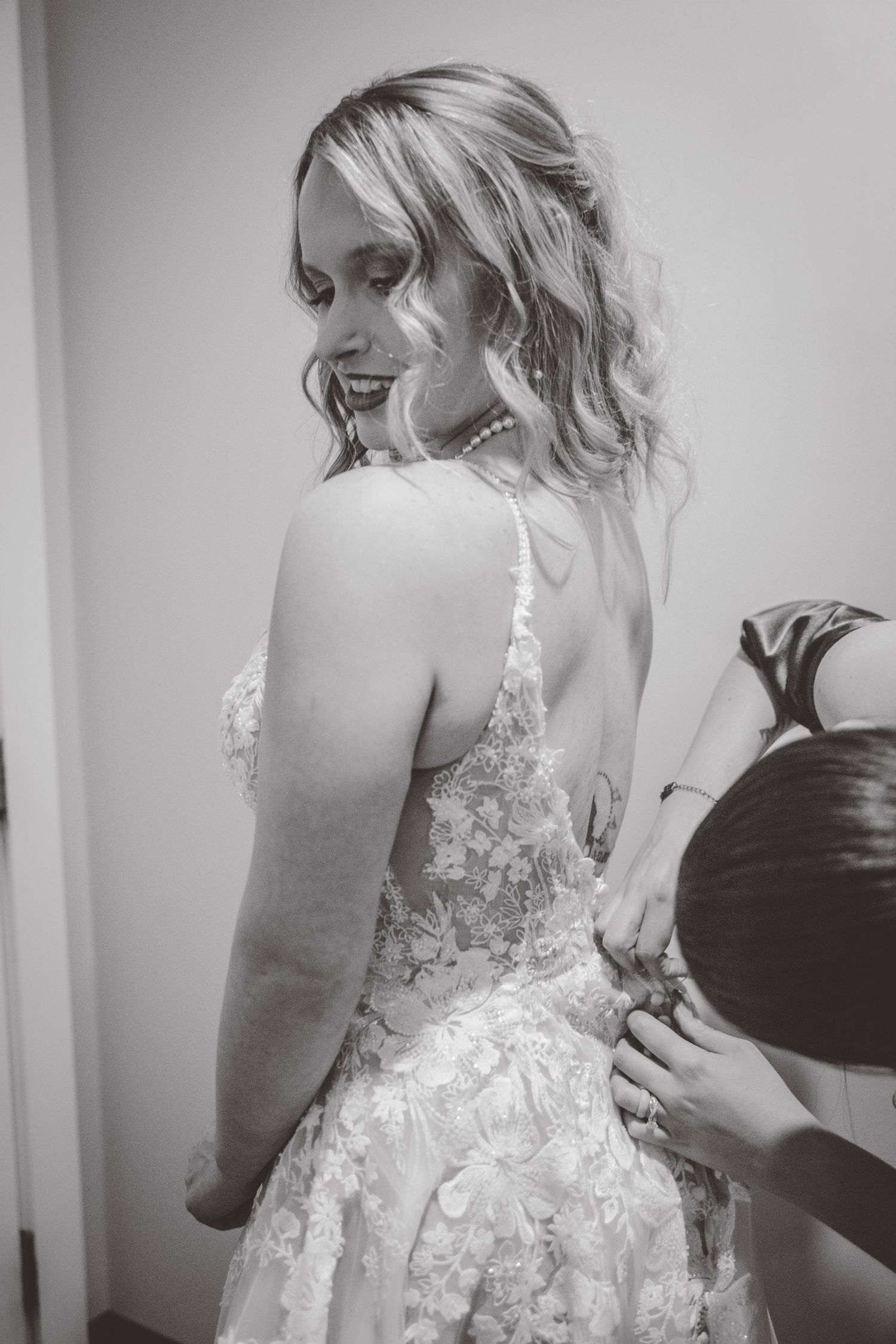 Close-up details of a bride getting dressed in an elegant white lace wedding gown.