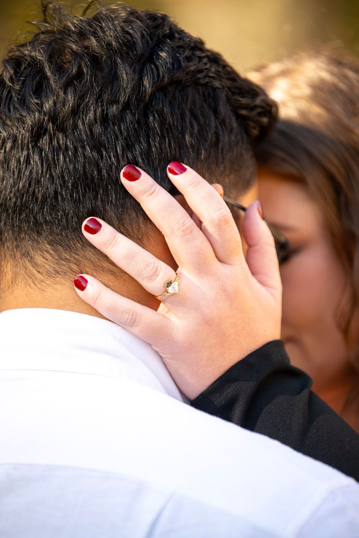 Intimate close-up showing hands with red nail polish during romantic moment.