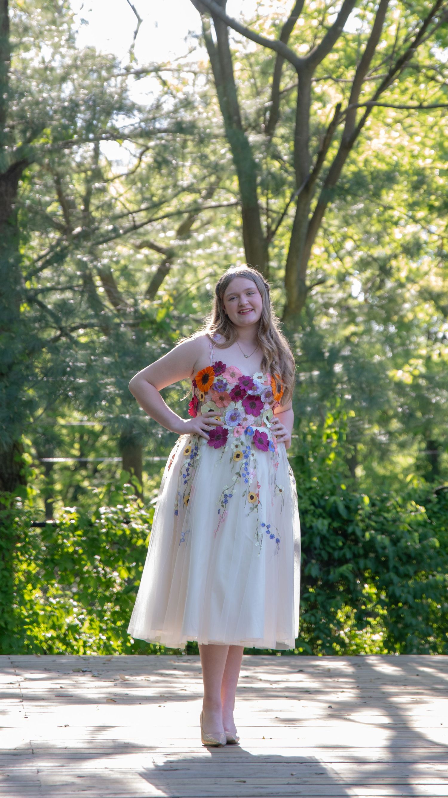 Outdoor portrait sequence in white dress with colorful flowers against sunlit garden backdrop.