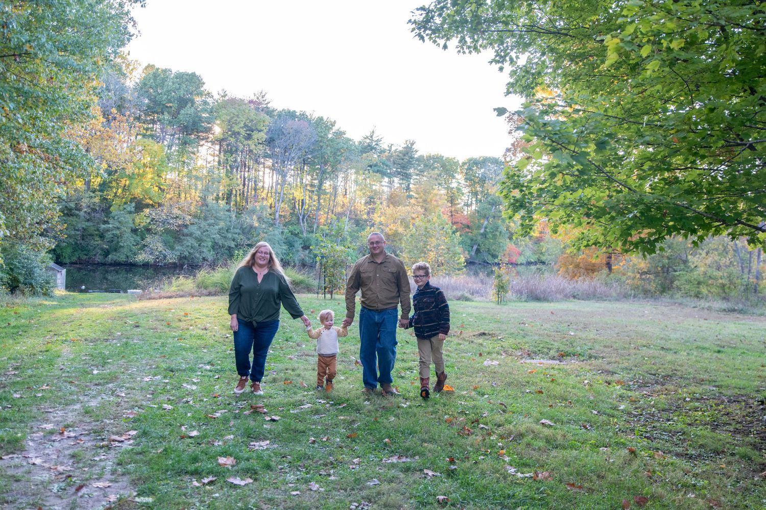 People strolling through a peaceful autumn landscape with trees and grass.