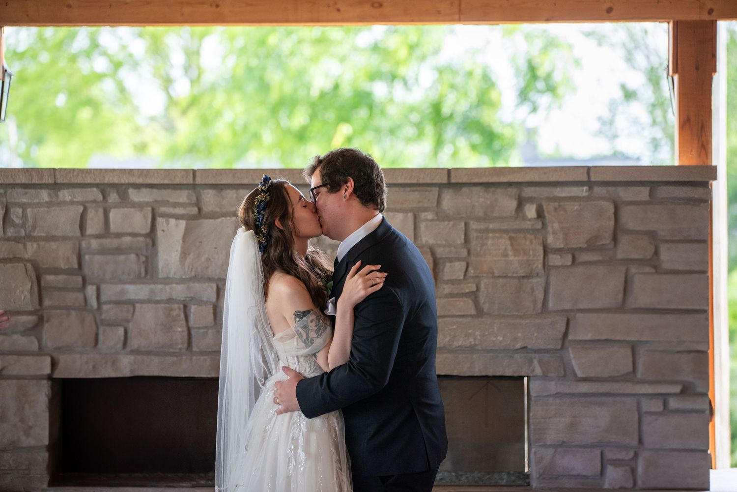 A romantic wedding moment captured against a stone wall backdrop with soft natural lighting.