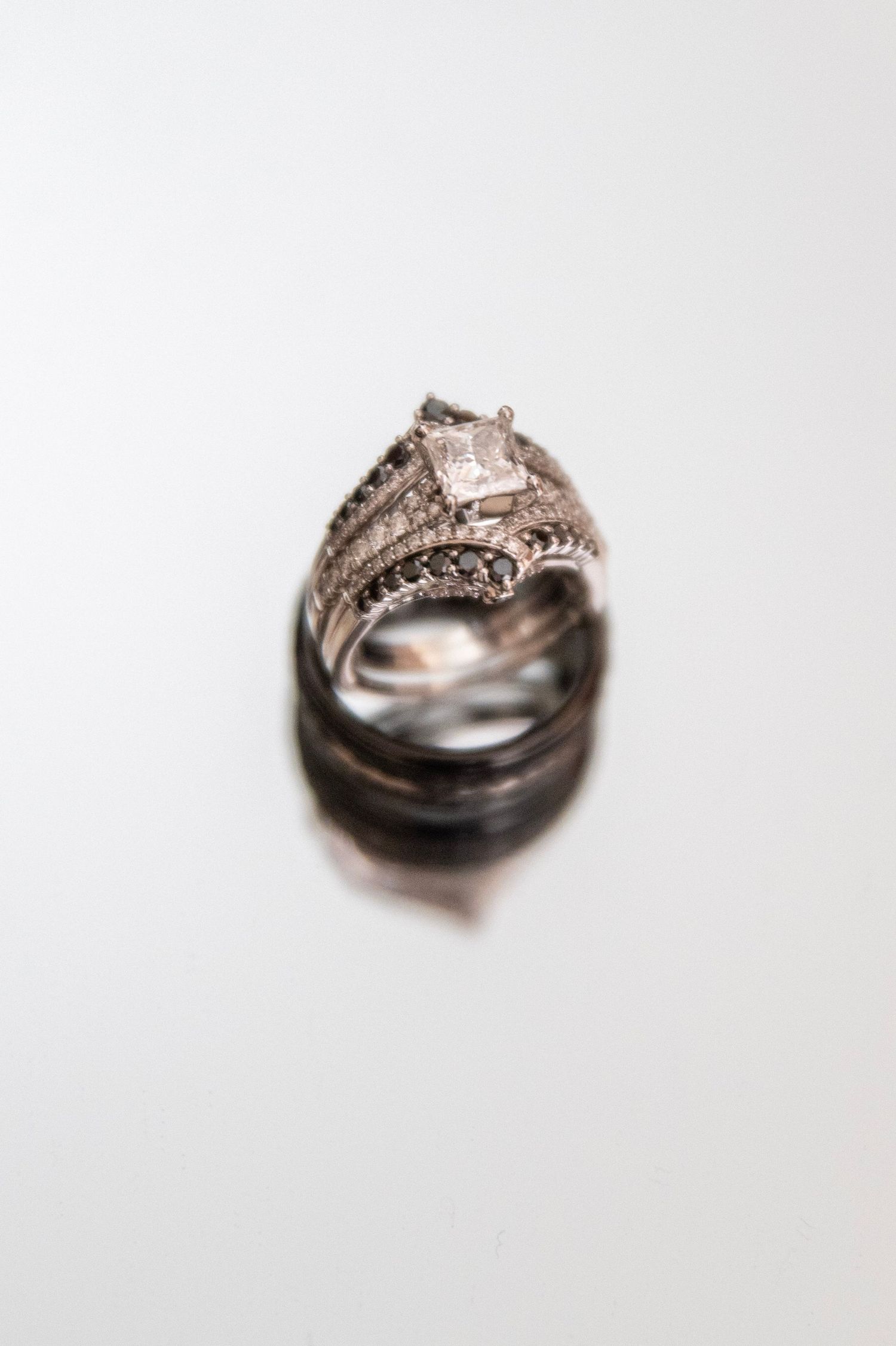 Close-up of vintage style diamond engagement ring and wedding band on white background.